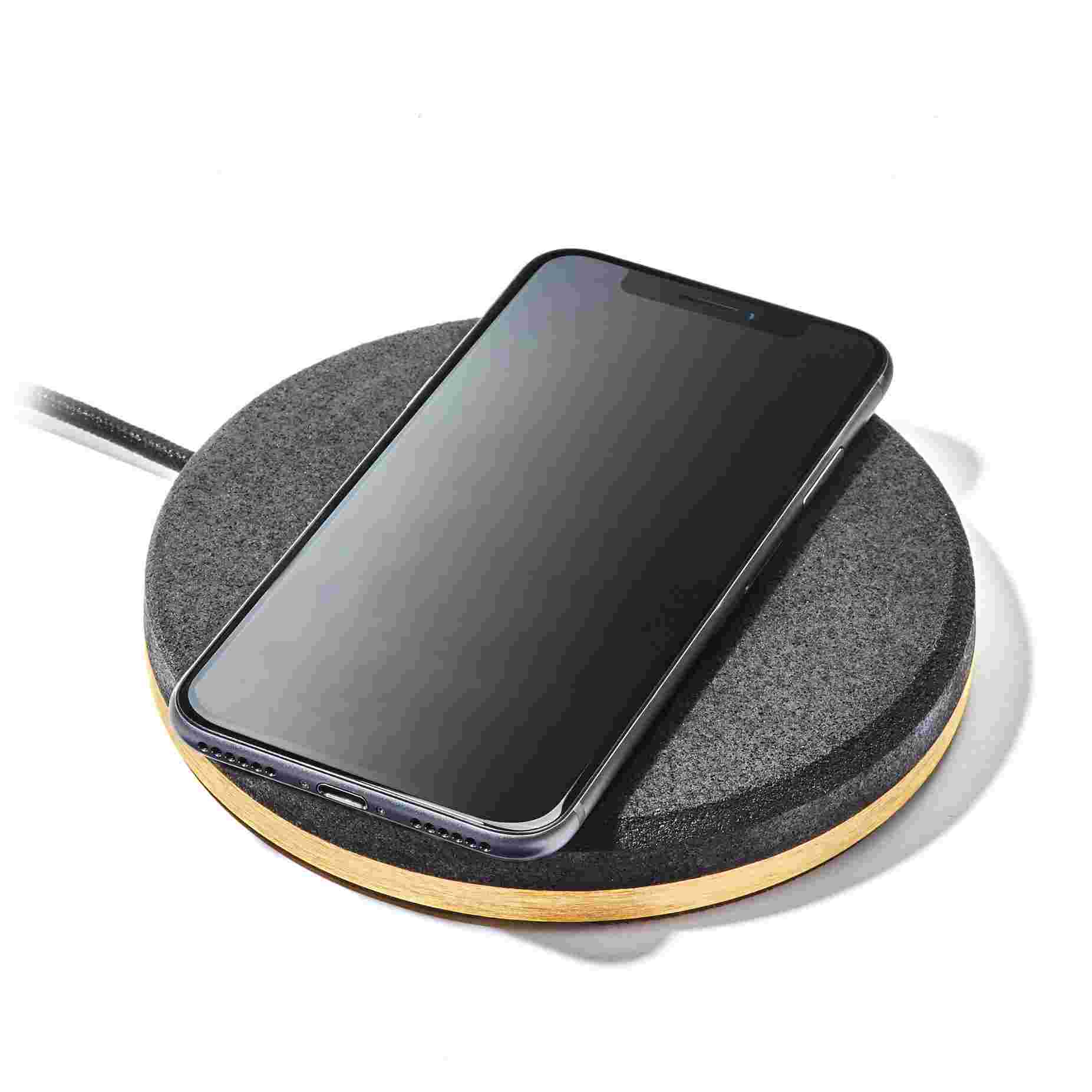 The Brass Wireless Charging Pad with dark cork top charging an iPhone X.
