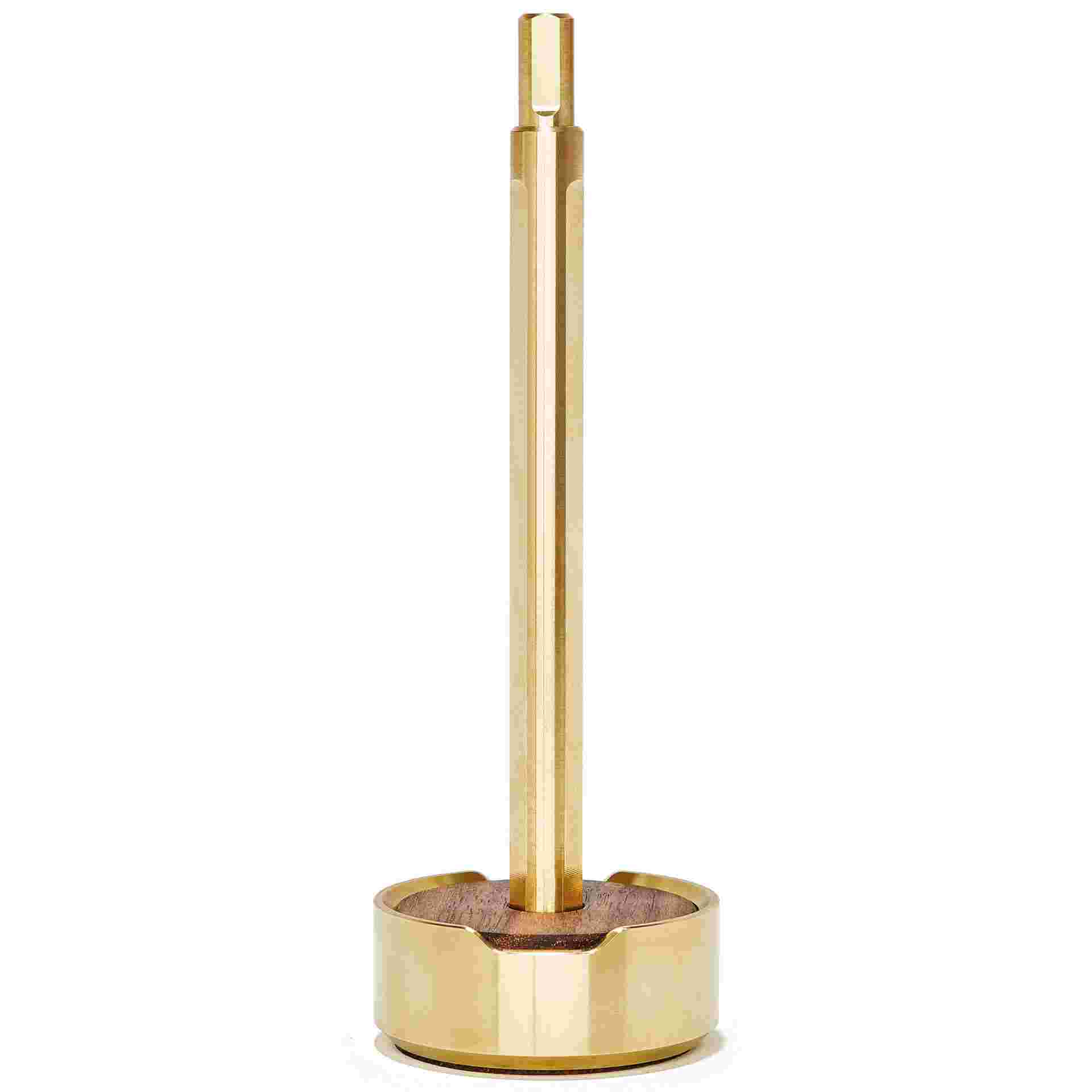 Starkly minimalist brass pen set upright in walnut wood and brass stand.