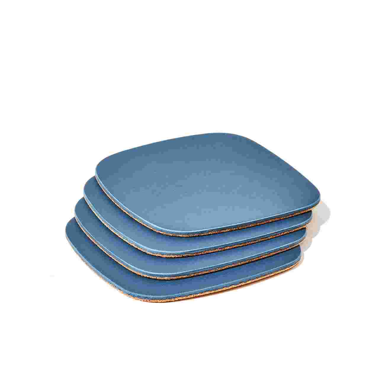 Stack of four matte navy blue coasters with cork padding.
