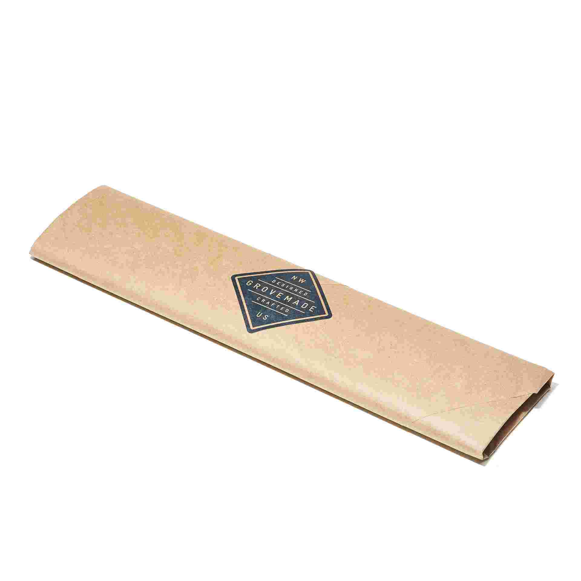 The Leather and Walnut Wrist Pad gift-wrapped in brown craft paper.
