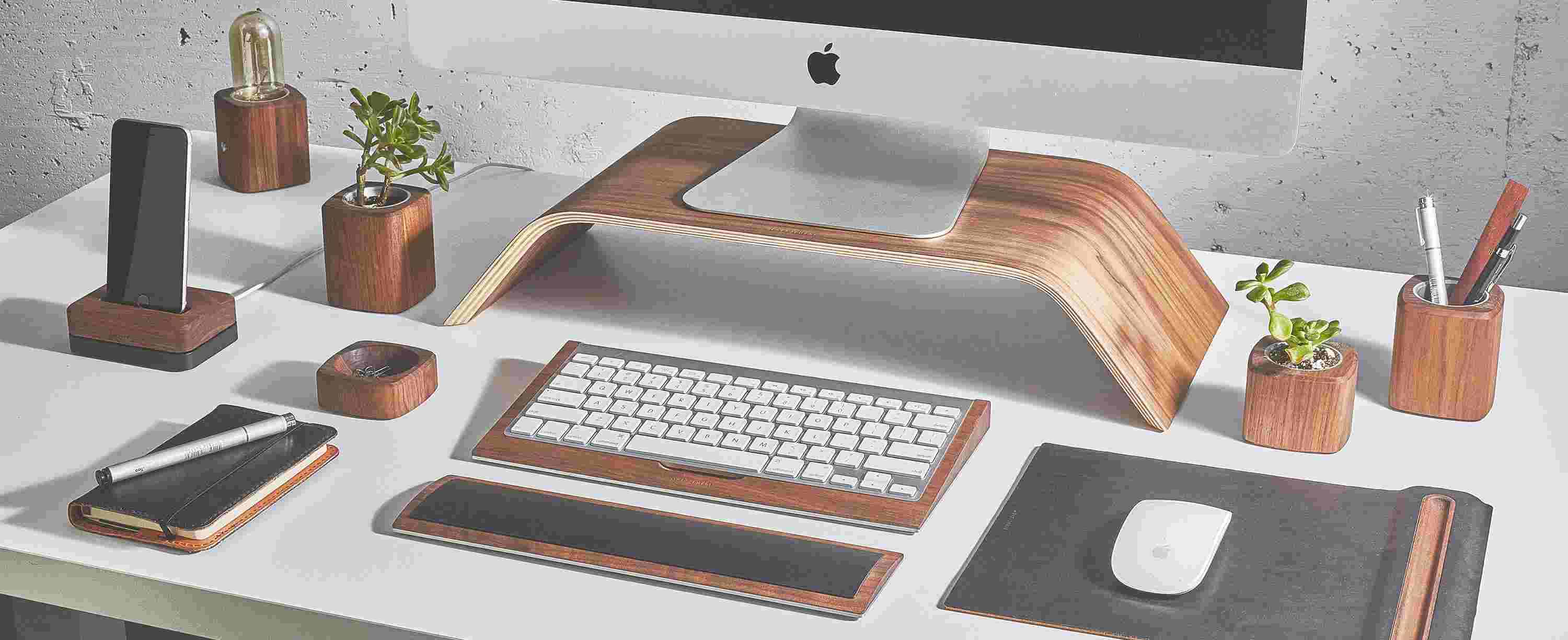 The original Grovemade Desk Collection featuring bent-wood monitor stand, leather mouse pad, walnut keyboard tray, and various planters and lamps.