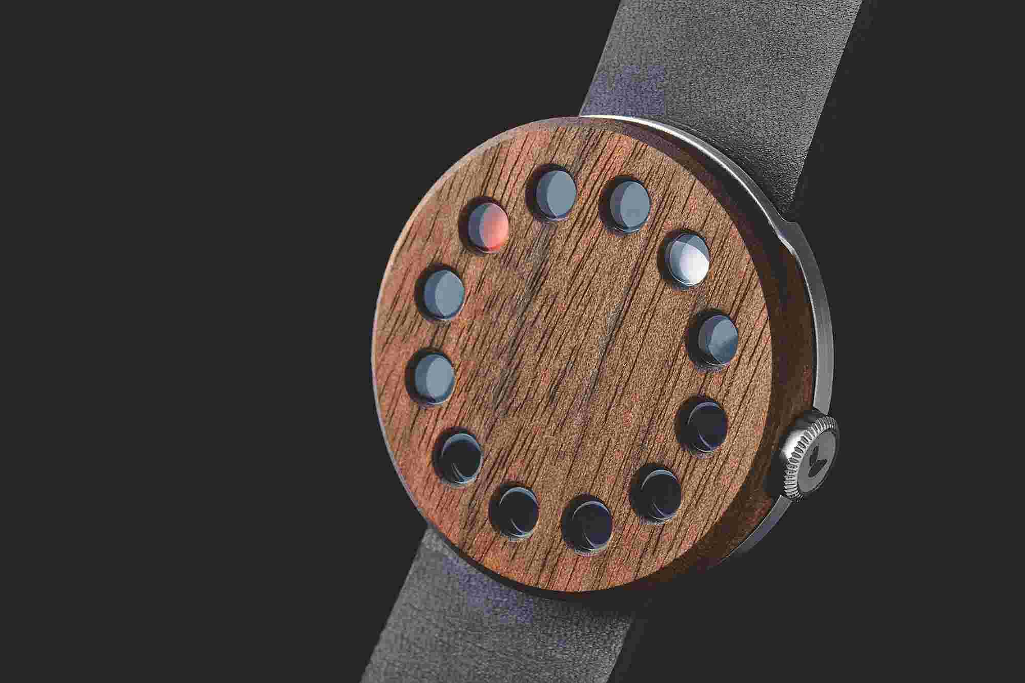 Walnut face of the unique Grovemade Watch 01, featuring 12 circular windows that reveal two different colors representing hours and minutes.