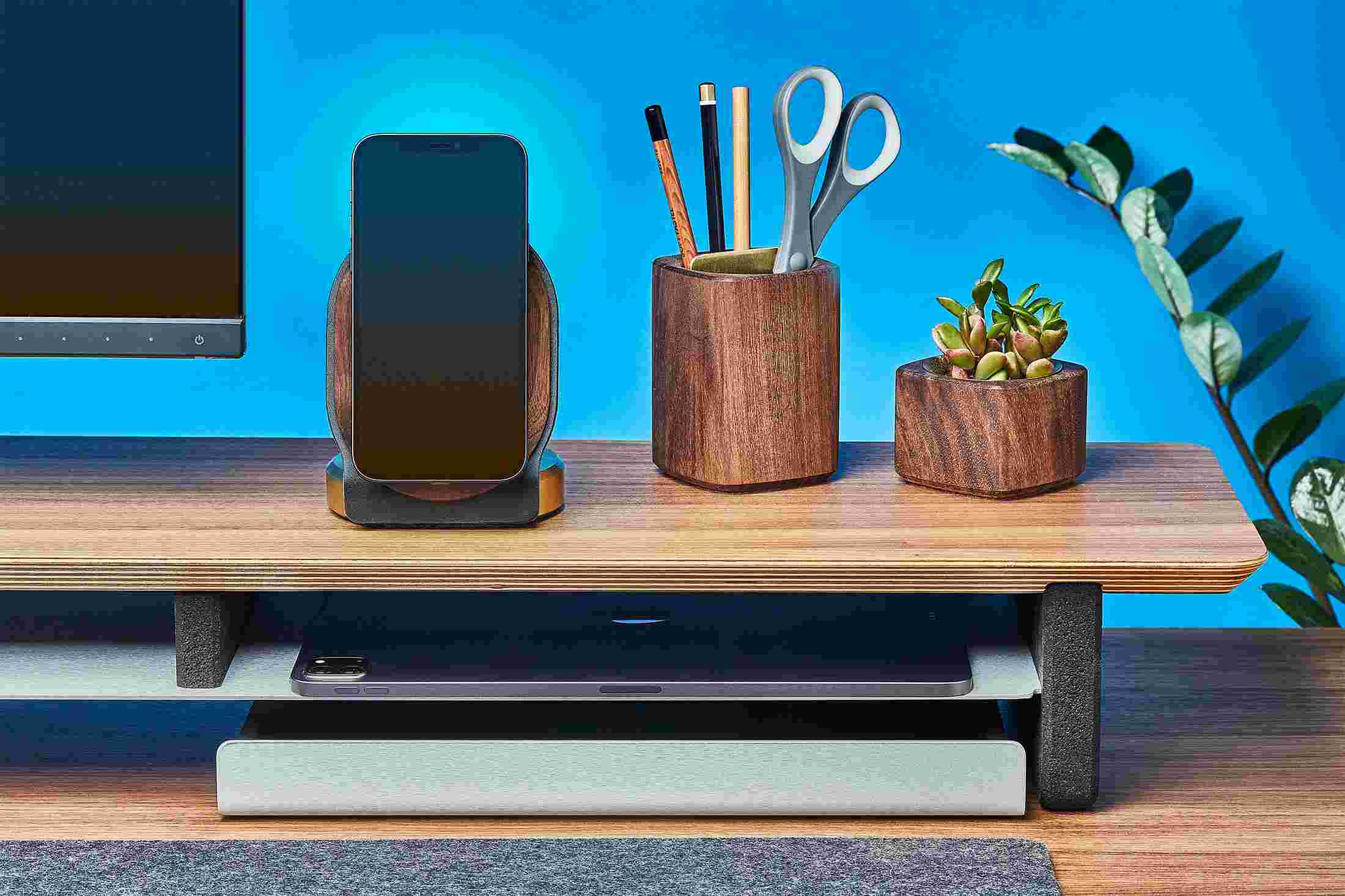Brass MagSafe Stand for iPhone 12 on wood monitor stand alongside walnut planters and premium leather desk mat.