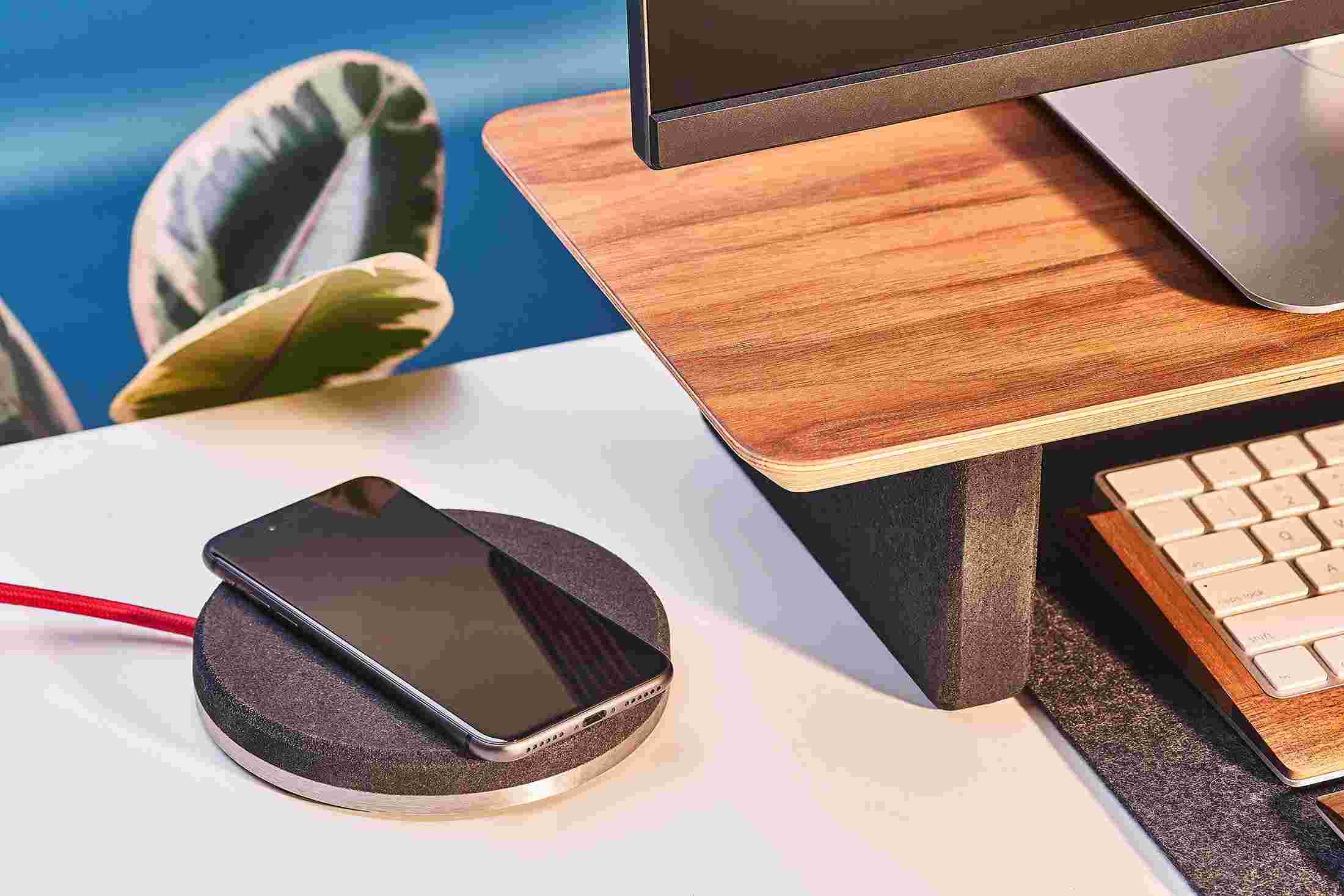 The iPhone Charging Pad topped with black cork, matching the black cork leg of the desk shelf.