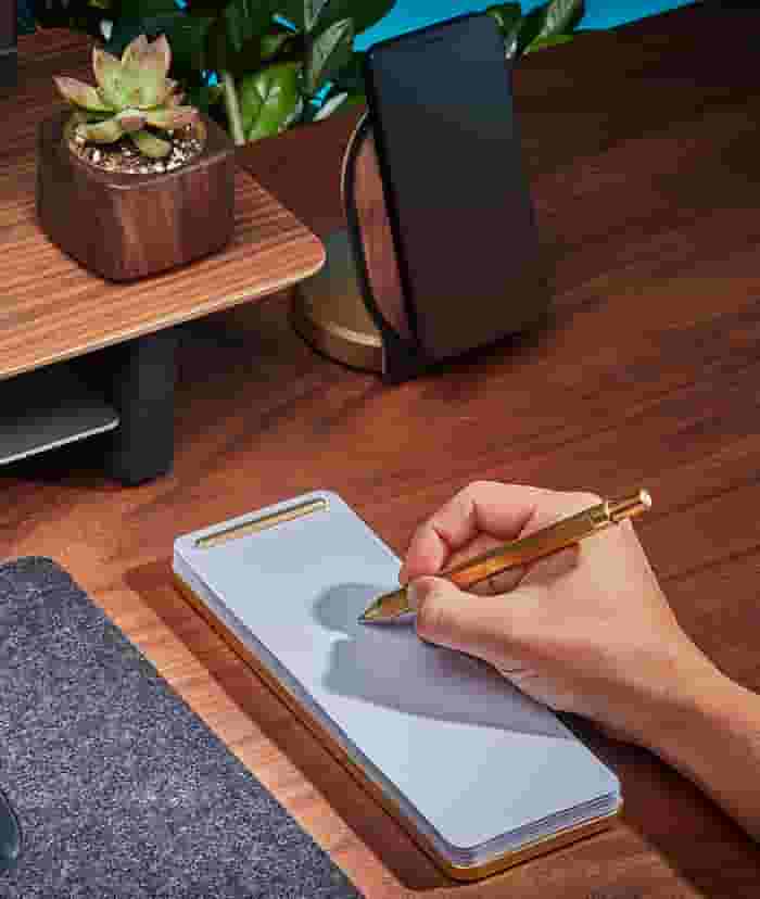 The slim brass notepad in use with the Grovemade Brass Pen.