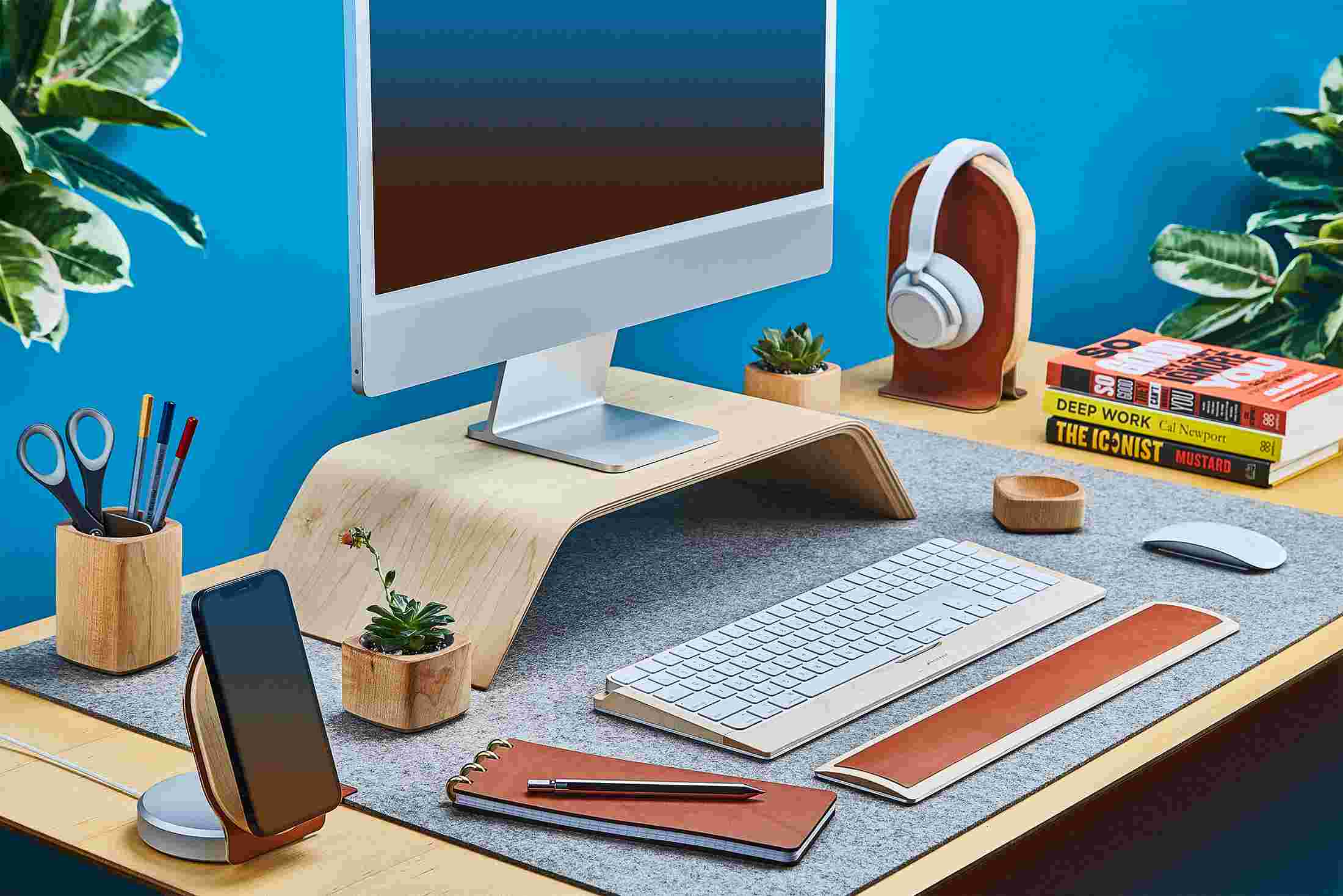 Side view of the maple wood Grovemade Desk Collection with maple wood monitor stand, pen cup, planters, leather wrist pad, and keyboard tray.