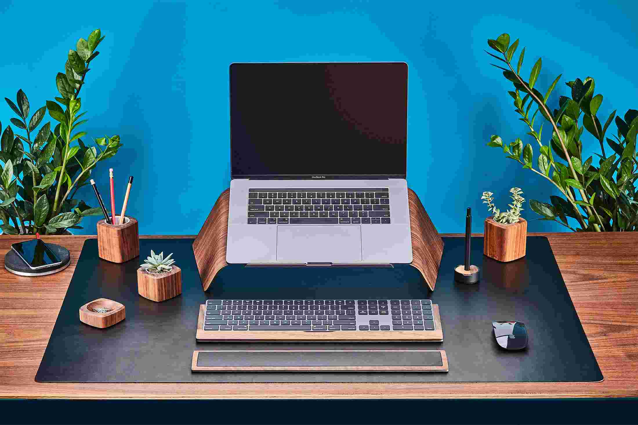 Walnut Wood Grovemade Desk Collection with walnut laptop stand, pen cups, desk lamps, planter, leather mouse pad, leather wrist pad, and keyboard tray.