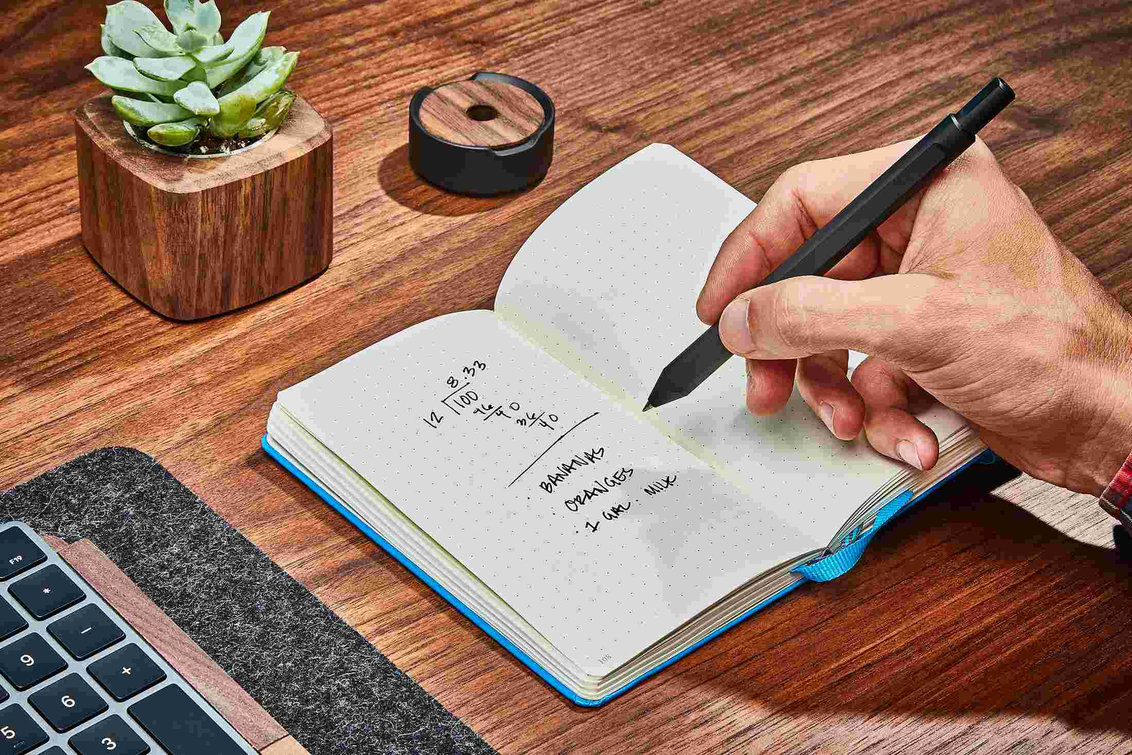 The Grovemade Black Pen in use, writing in a notebook.