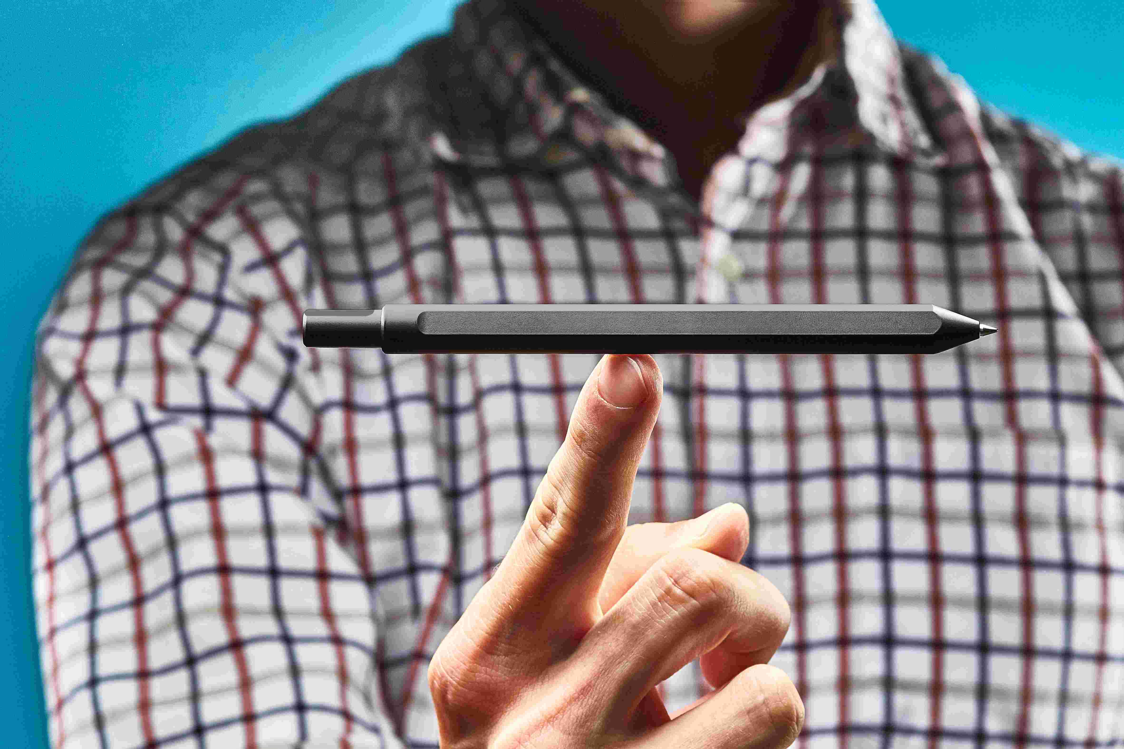 The black pen perched on a single finger, showing the extreme balance of the minimalist design.