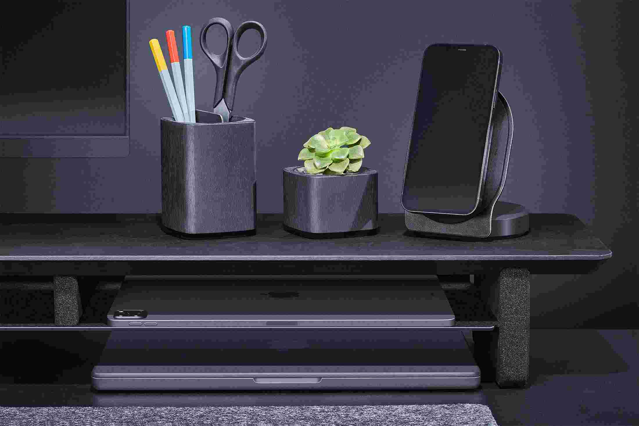 Blackened Walnut MagSafe Stand on black desk shelf alongside matching black accessories.