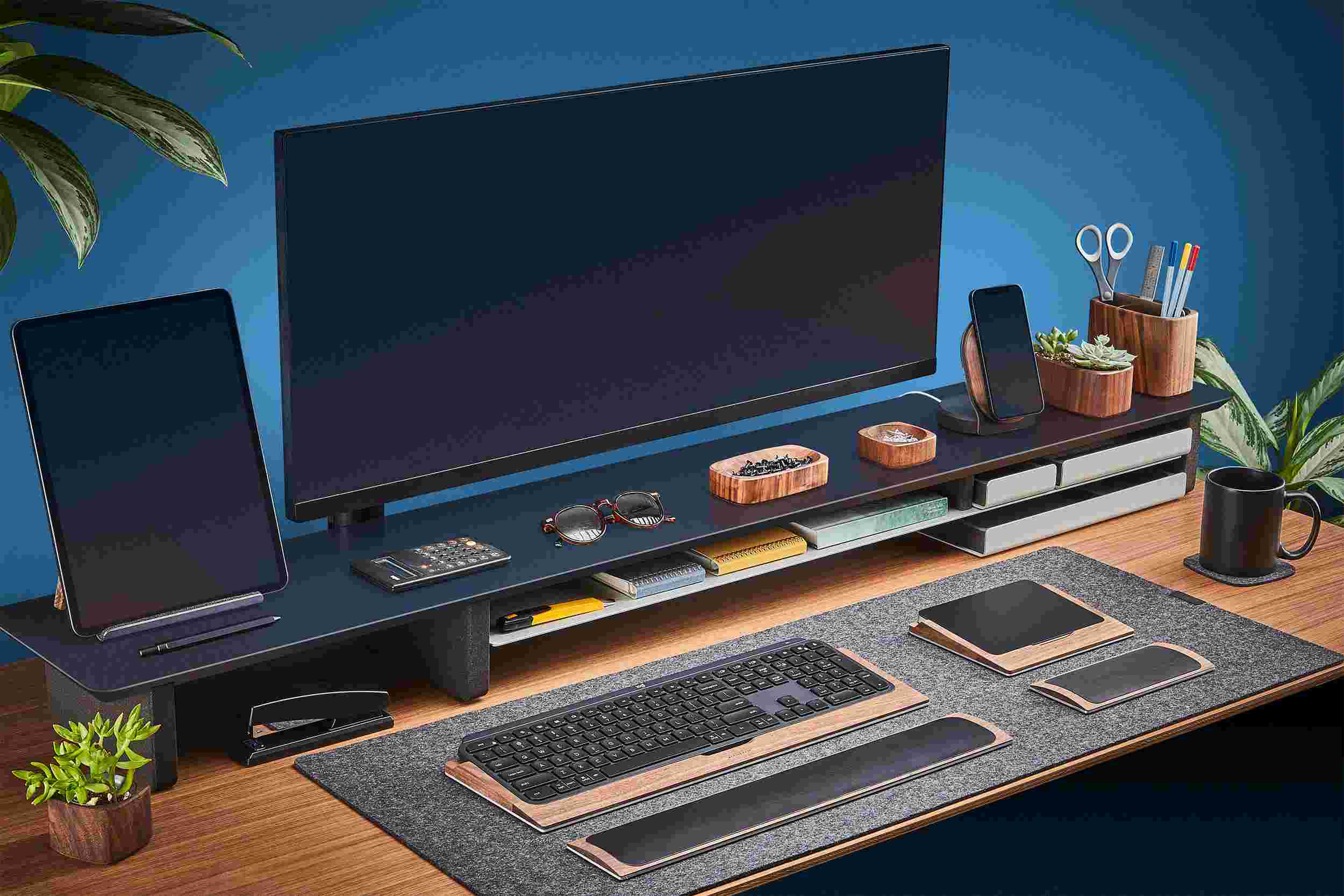 Ultra-wide matte black desk shelf for double monitor setup, with dark merino wool felt desk pad.