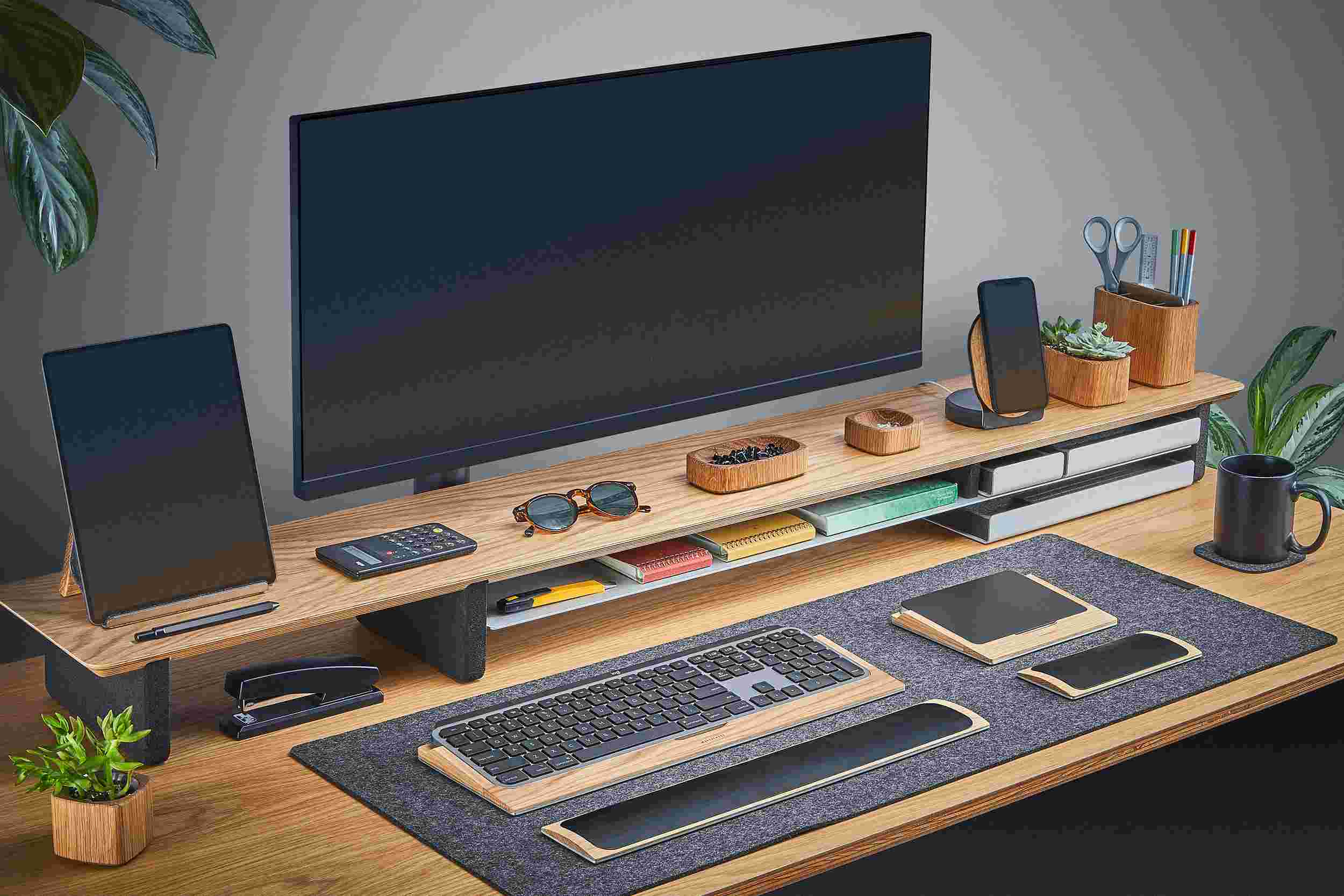 Ultra-wide oak plywood desk shelf for double monitor setup, with dark merino wool felt desk pad.