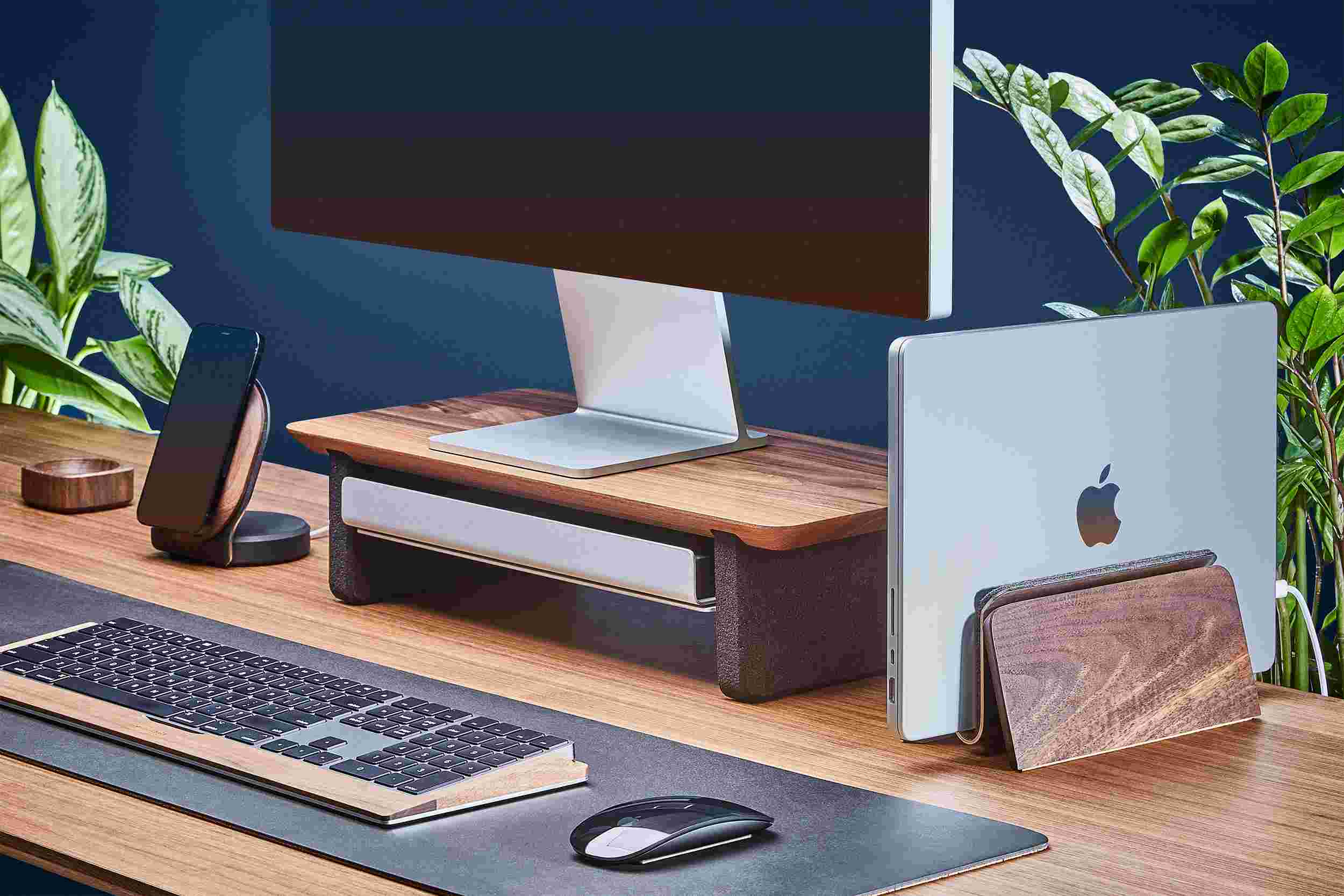 Space saving MacBook Dock and compact solid hardwood walnut monitor stand, with black leather desk pad.