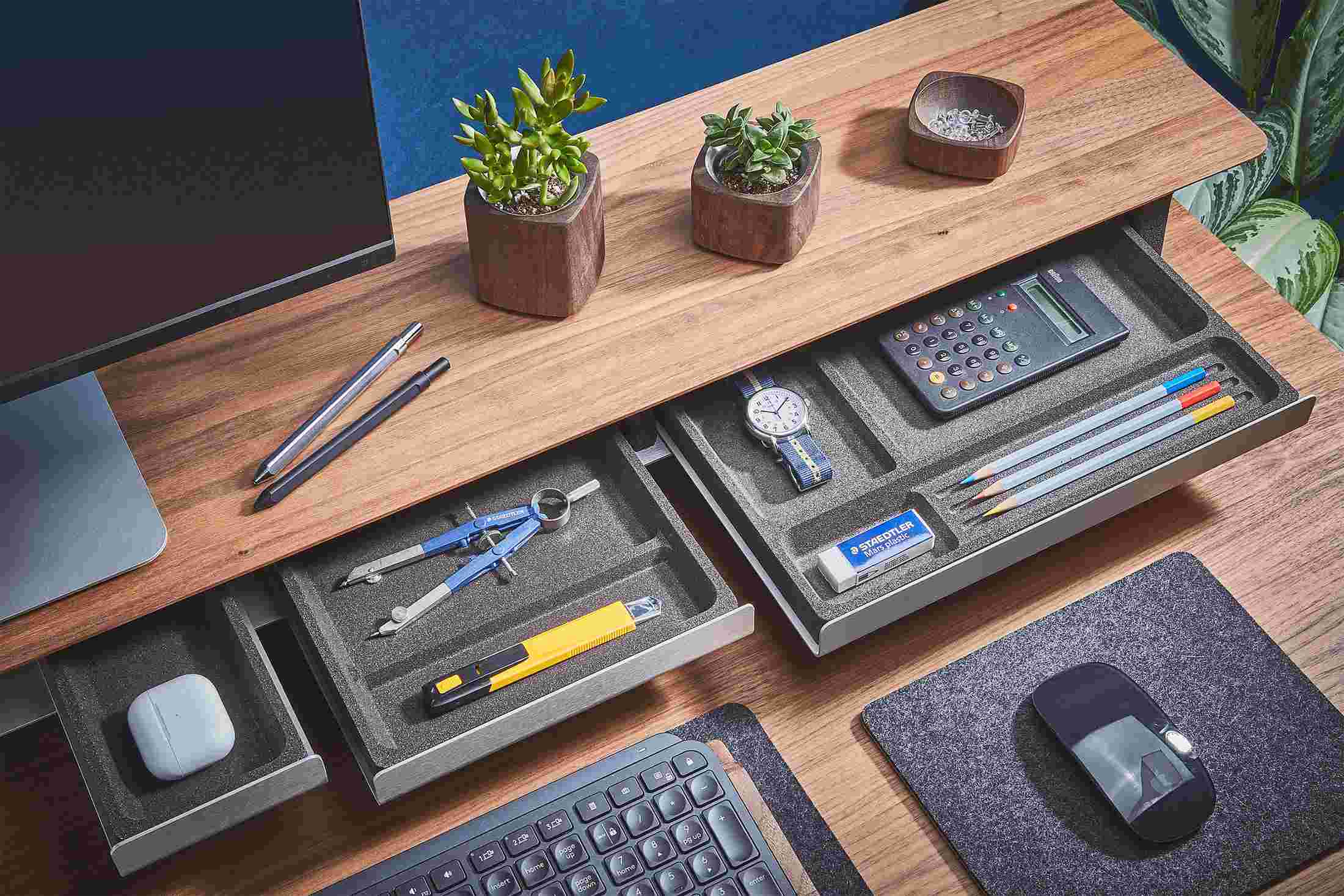 Small medium and large desk trays with varying sizes compartments, pulled out from a walnut desk shelf.