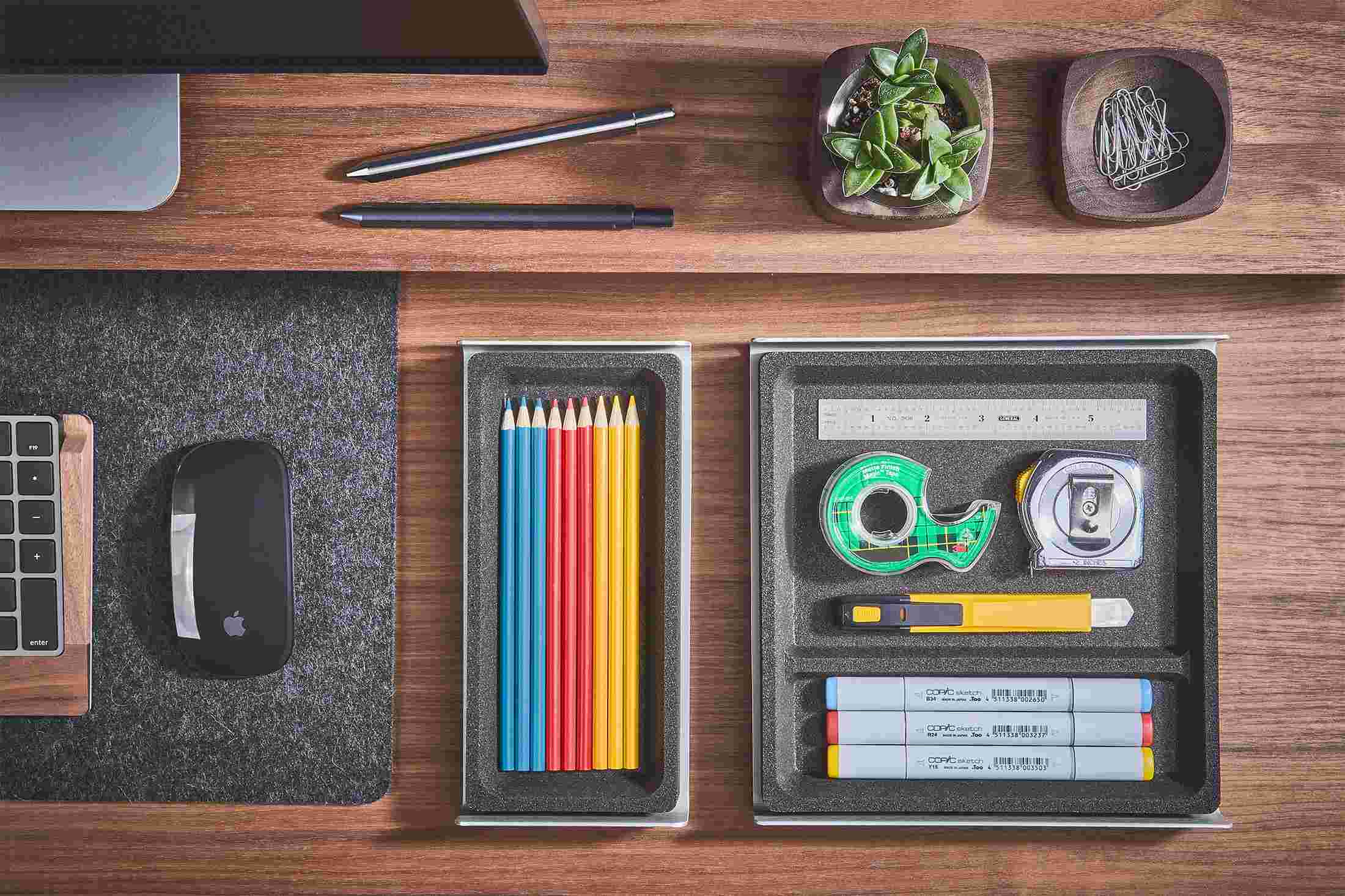 Overhead view of the small and medium dark cork desk trays, holding colored pencils and office supplies.