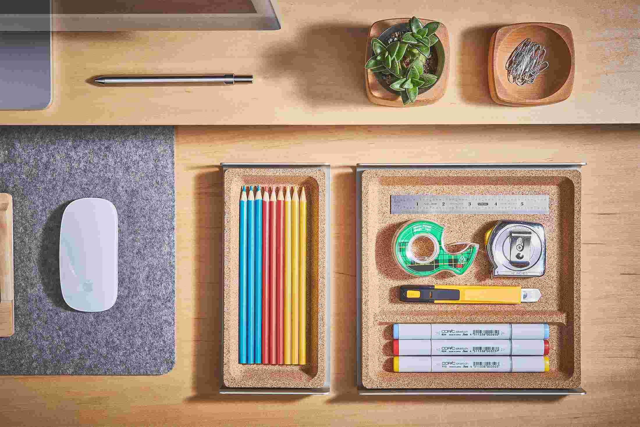 Overhead view of the small and medium light cork desk trays, holding colored pencils and office supplies.