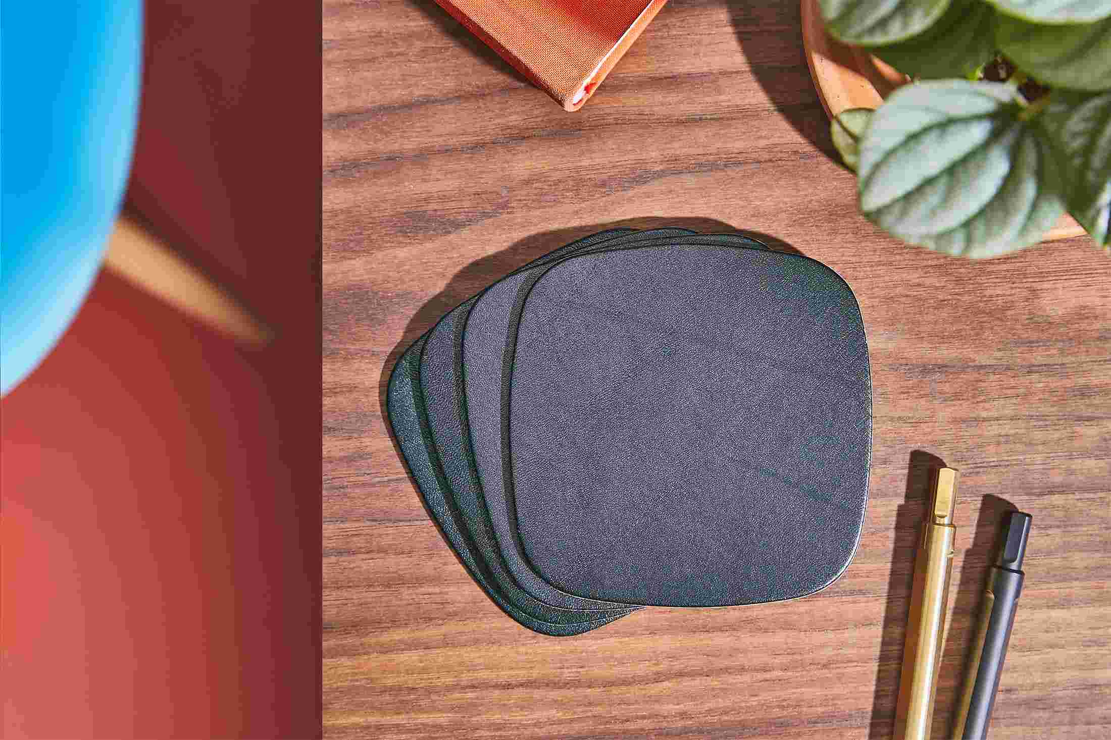 Overhead shot of a set of four premium black leather coasters.