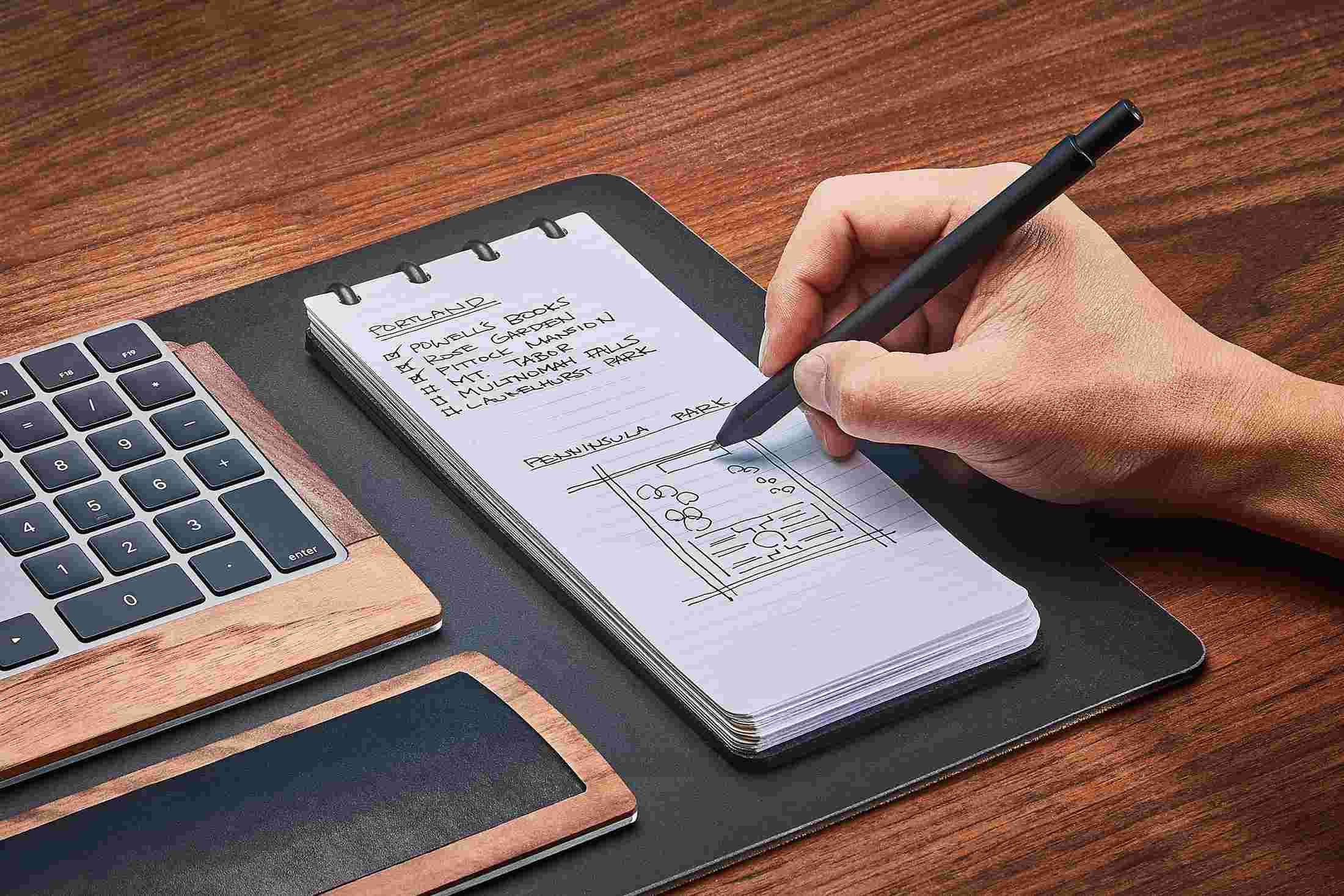 Black leather reporter style notebook with cover folded fully back for compact writing.