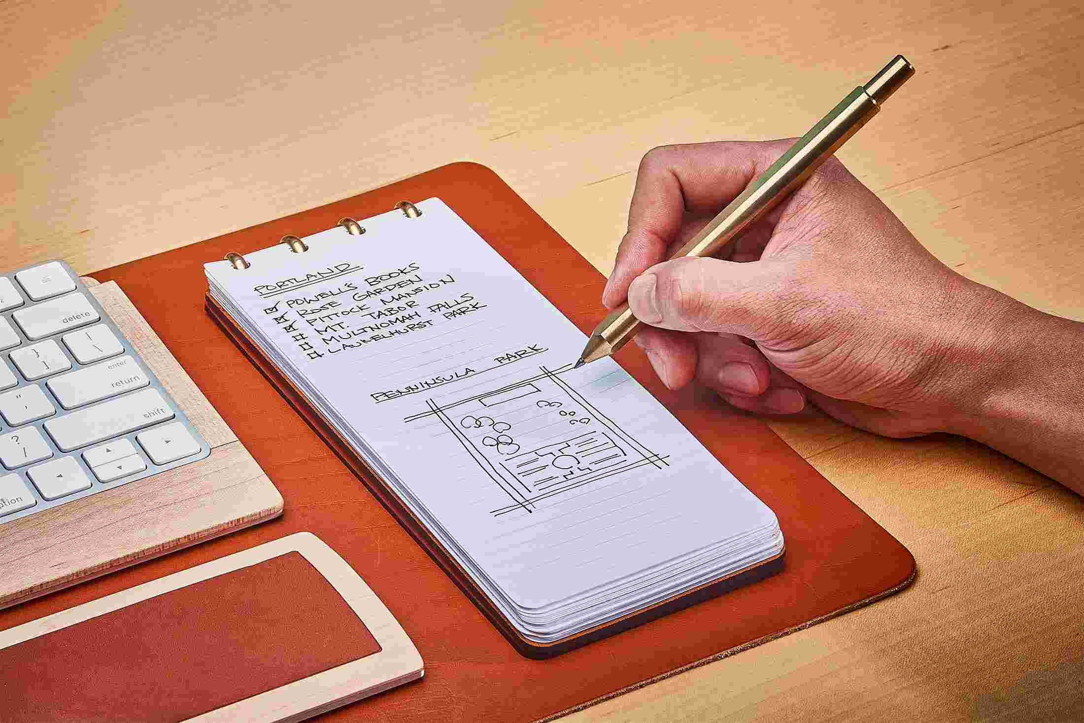 Tan leather reporter style notebook with cover folded fully back for compact writing.
