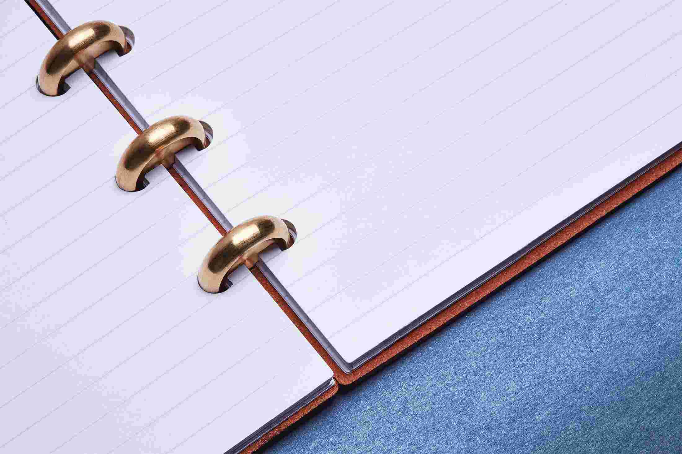 Close up detail showing the ruled notebook lying completely flat on blue linoleum.