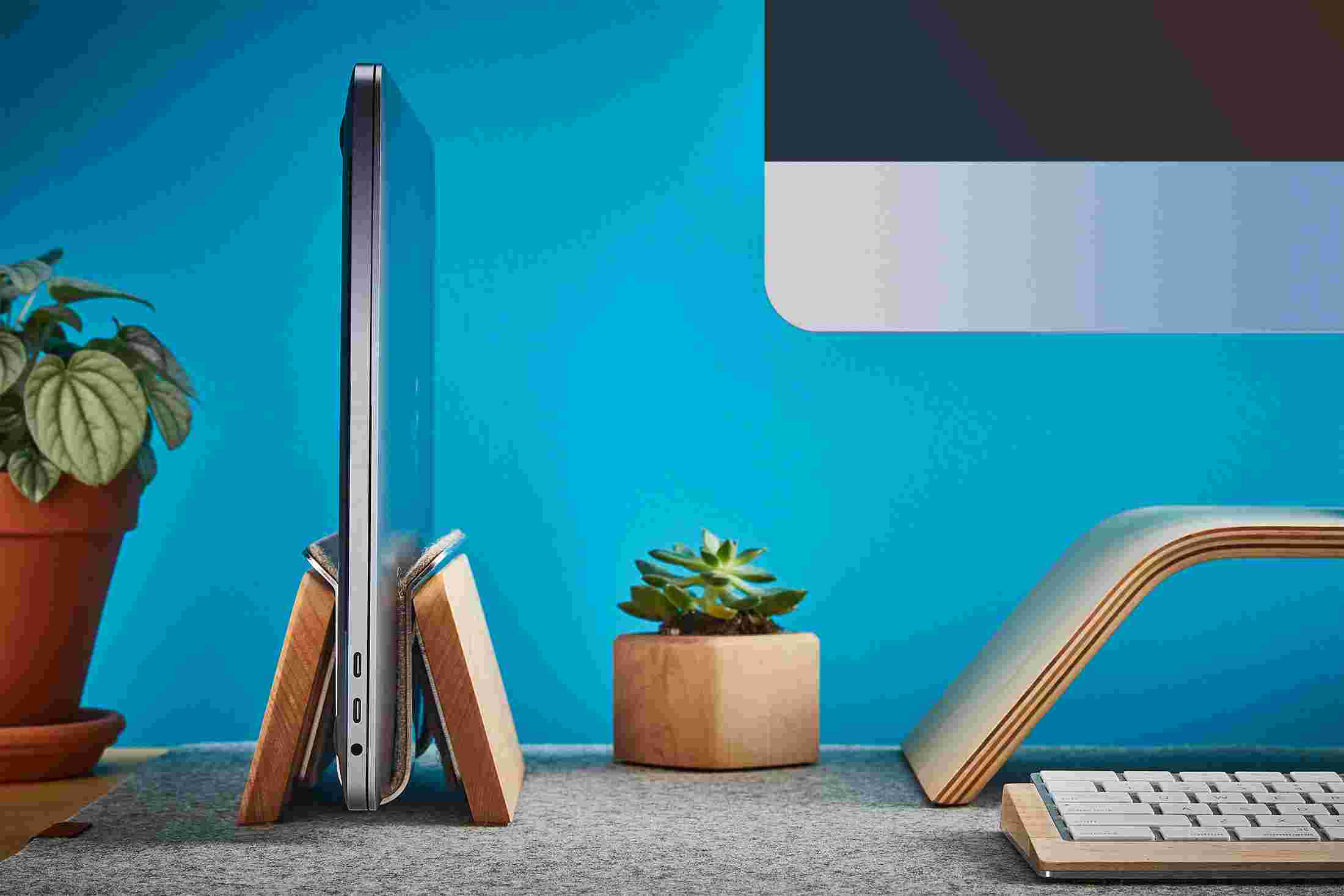 Profile view of the Maple Vertical MacBook Stand on wool felt desk pad.