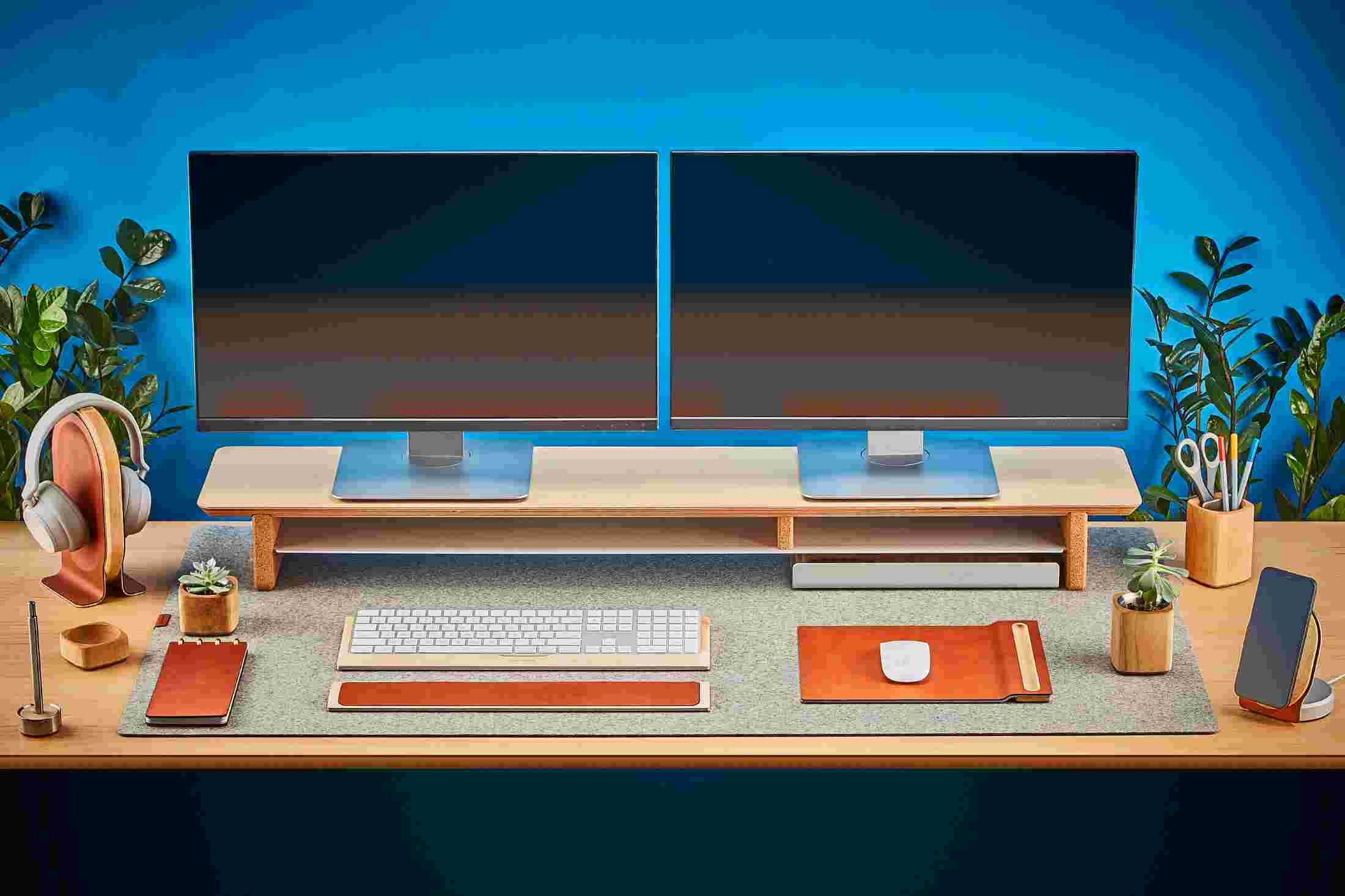 Front view of the maple wood Grovemade Desk Collection with maple leather and cork mouse pad, monitor stand, pen cups, desk lamps, planter, leather wrist pad, and keyboard tray.