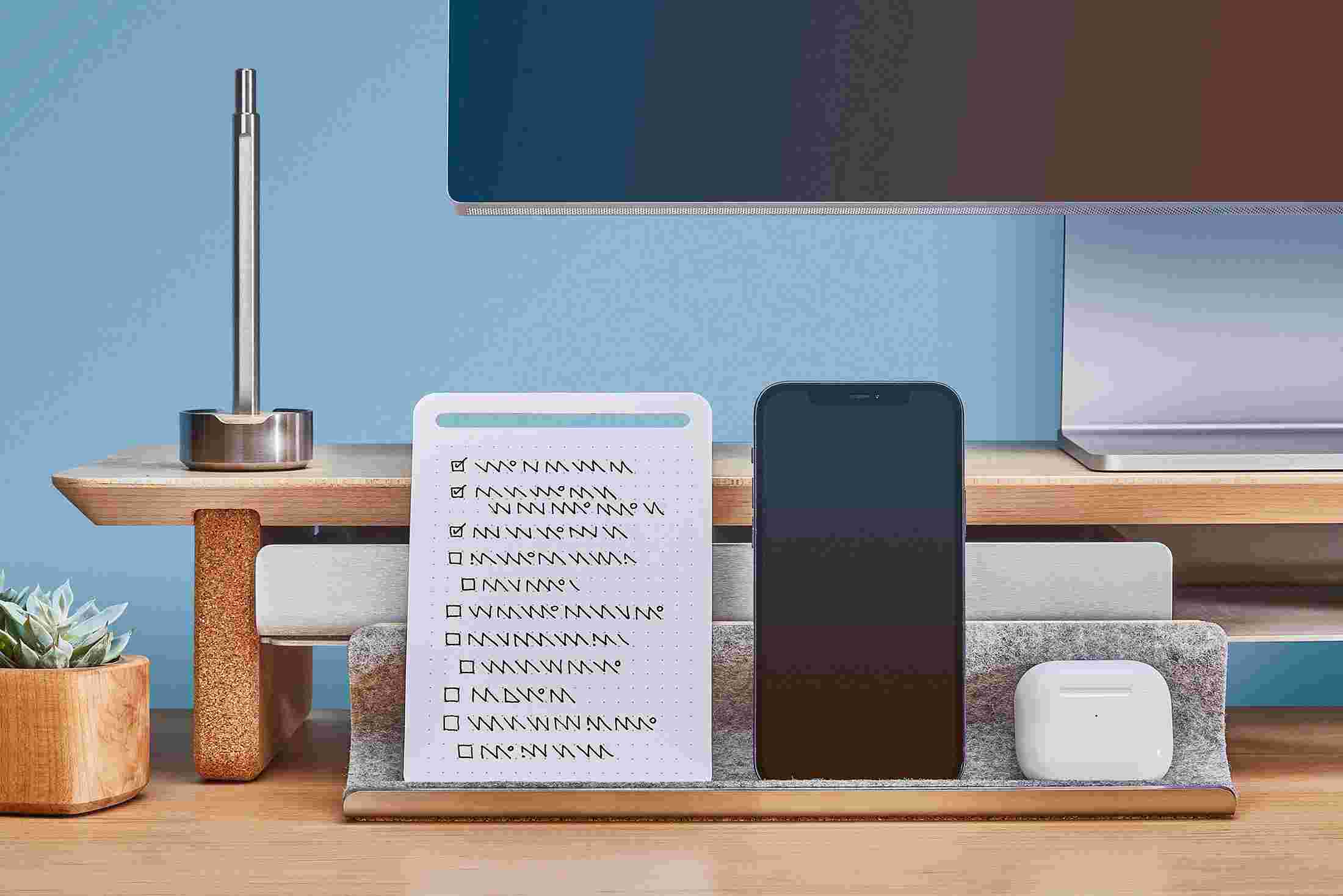 The Maple Display Rail propping up an iPhone and notes, and acting as a home for an AirPods case.