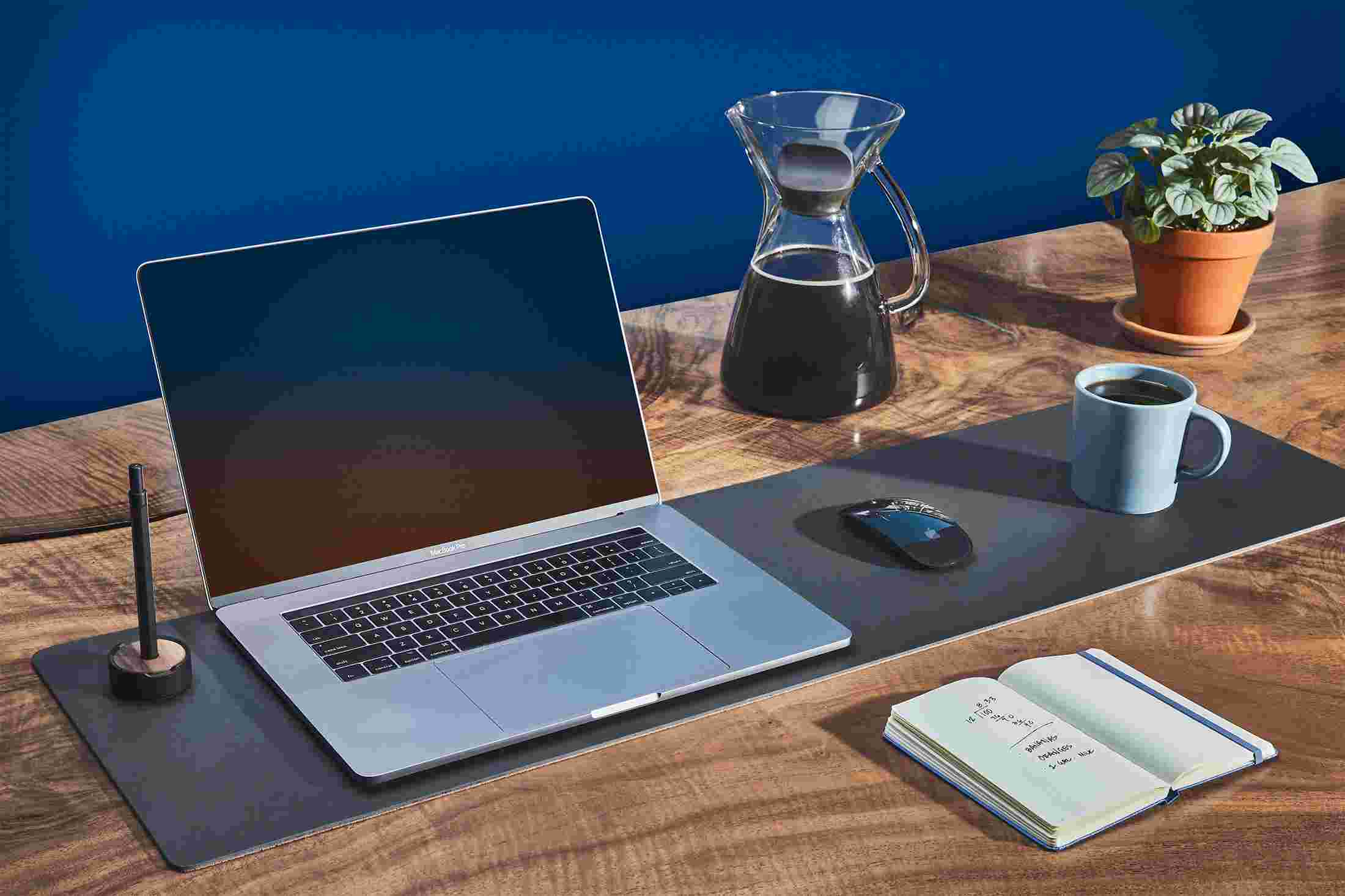 The medium matte black desk pad used as a combination laptop pad, mousepad, and coffee coaster.