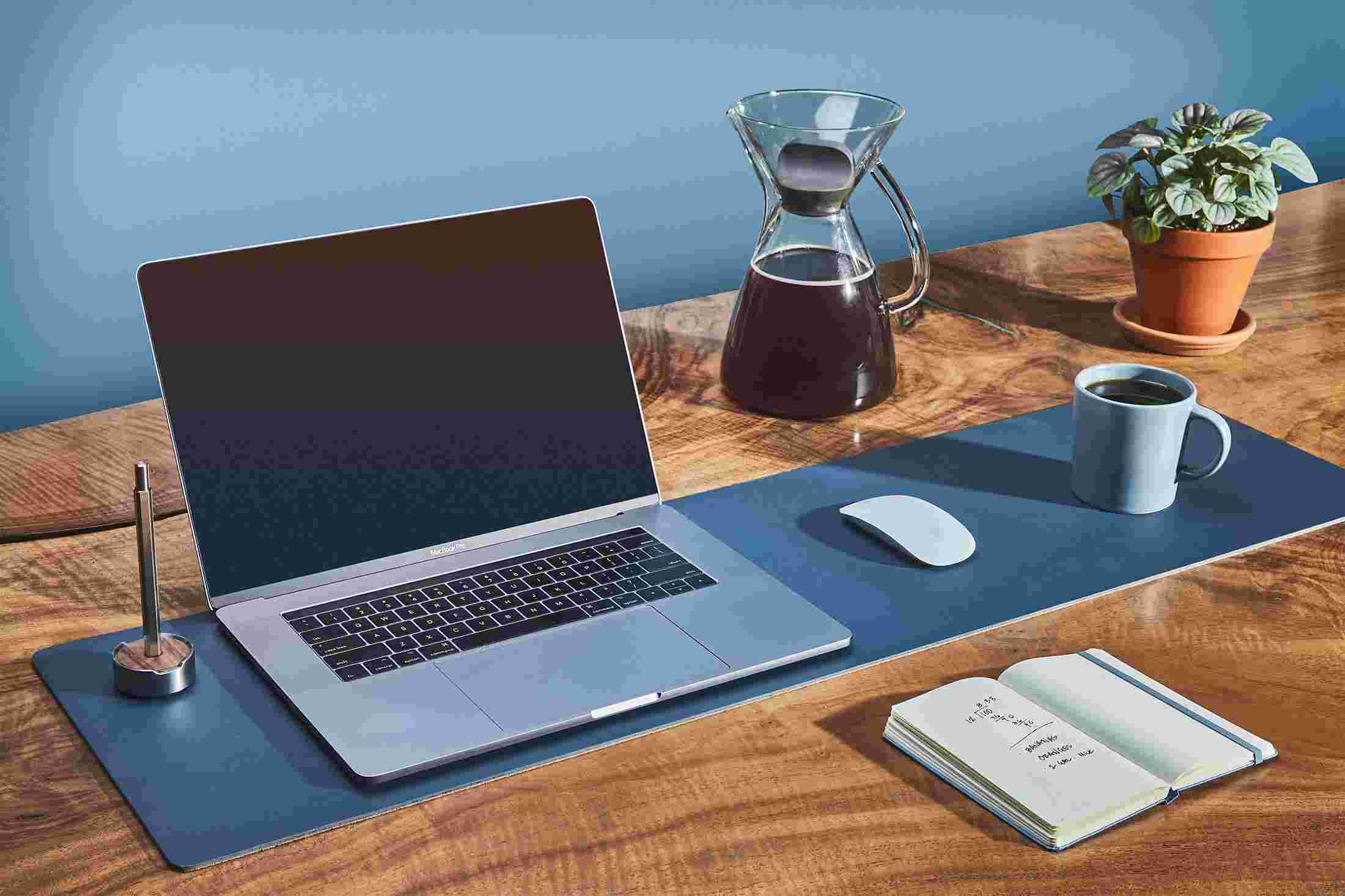 The medium matte navy blue desk pad used as a combination laptop pad, mousepad, and coffee coaster.