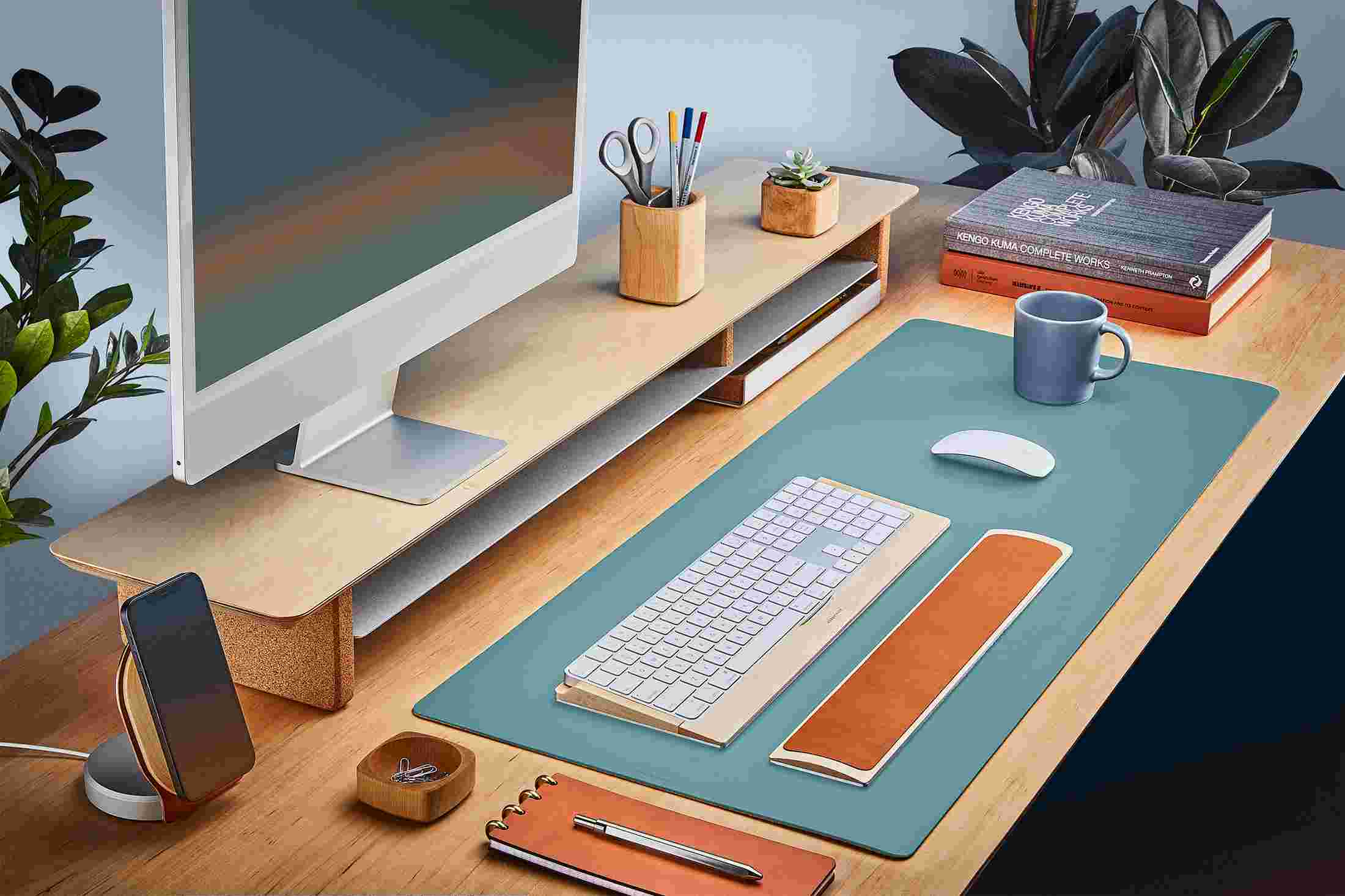 The Medium Matte Desk Pad in Light Blue runs the entire width of a standard desk, pictured here with walnut wood double-wide monitor stand.