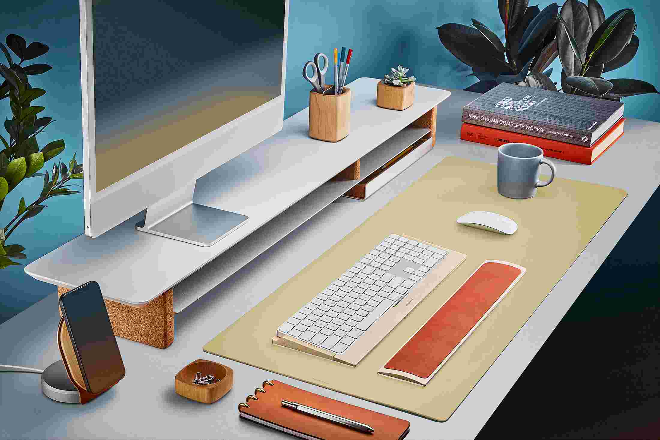 The Medium Matte Desk Pad in Light Yellow runs the entire width of a standard desk, pictured here with matte white double-wide monitor stand.