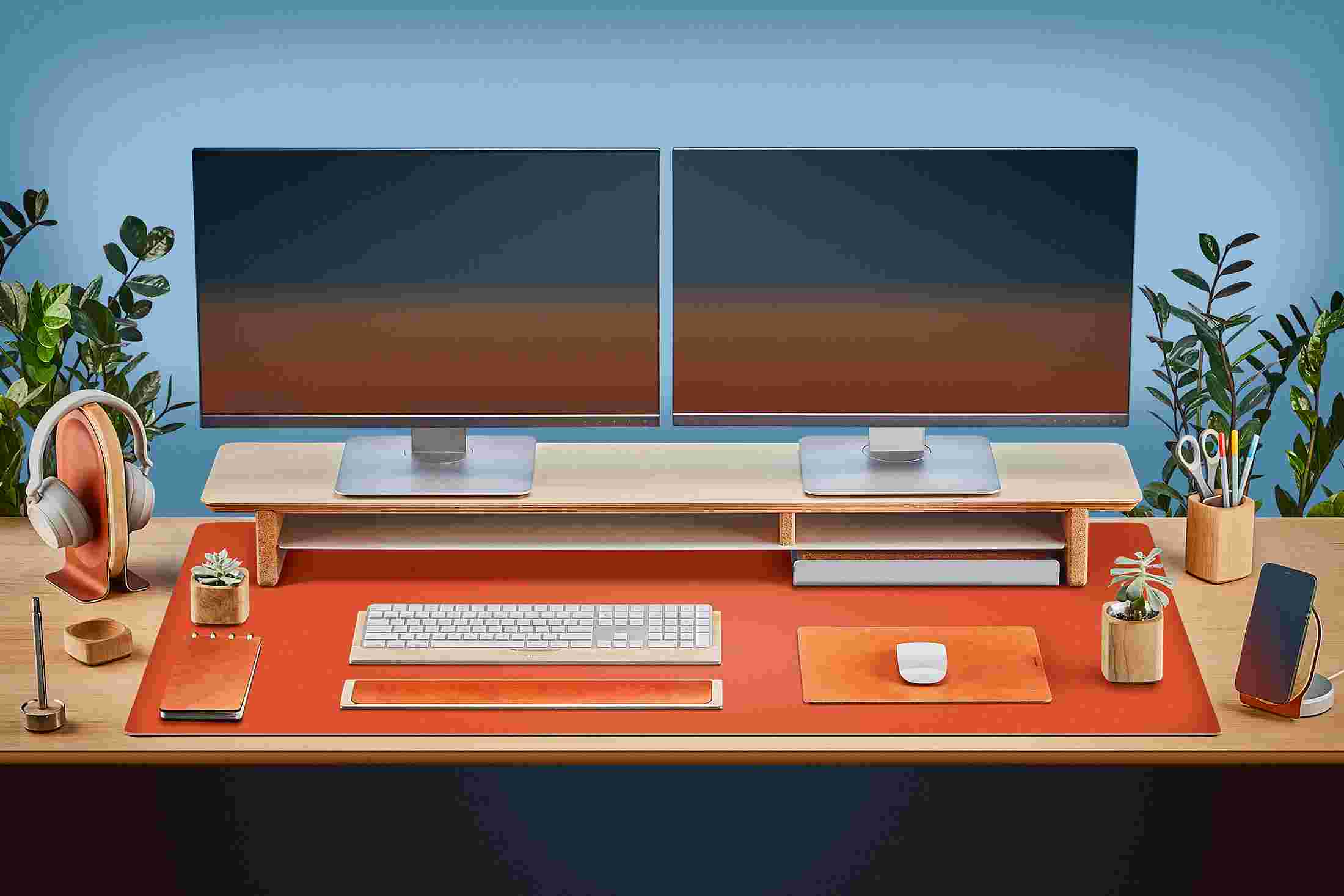 The Extra Large Matte Desk Pad in Orange covering almost an entire desktop, in use with the Matte Black Desk Shelf System.
