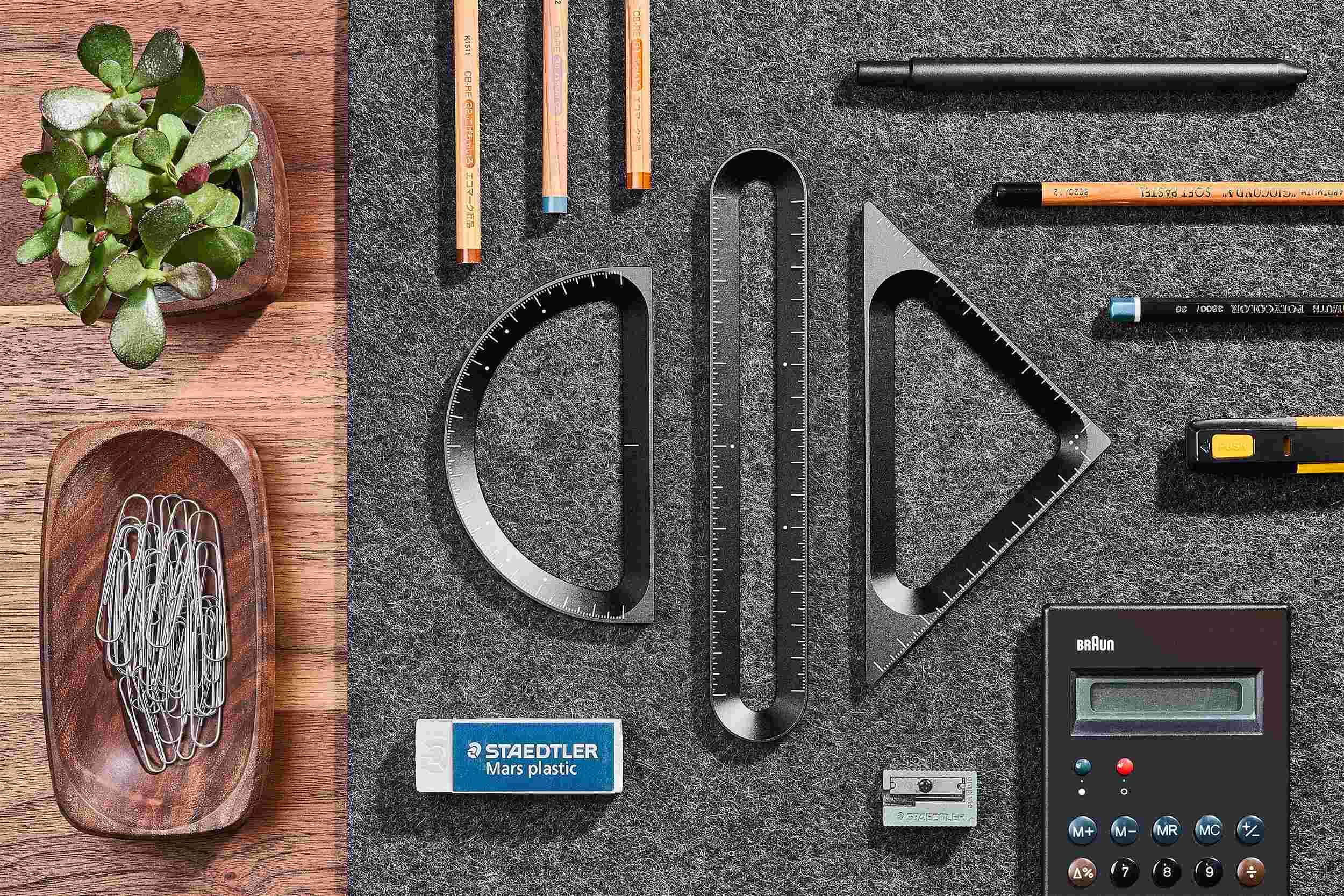 Overhead view of the Grovemade Measure Collection, on dark grey desk pad surrounded by pens and stationery.