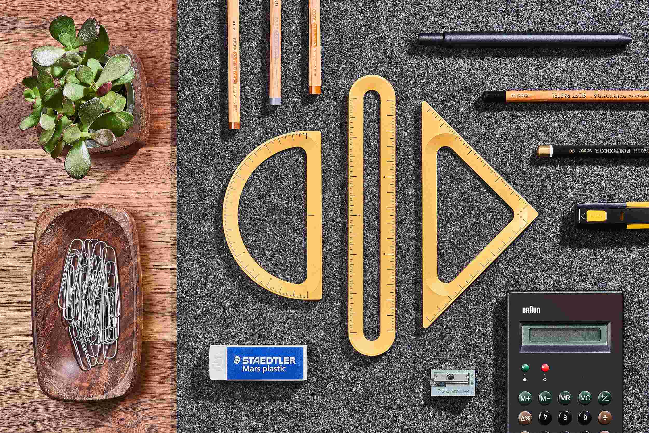Overhead view of the Grovemade Measure Collection in silver, on dark grey desk pad surrounded by pens and stationery.