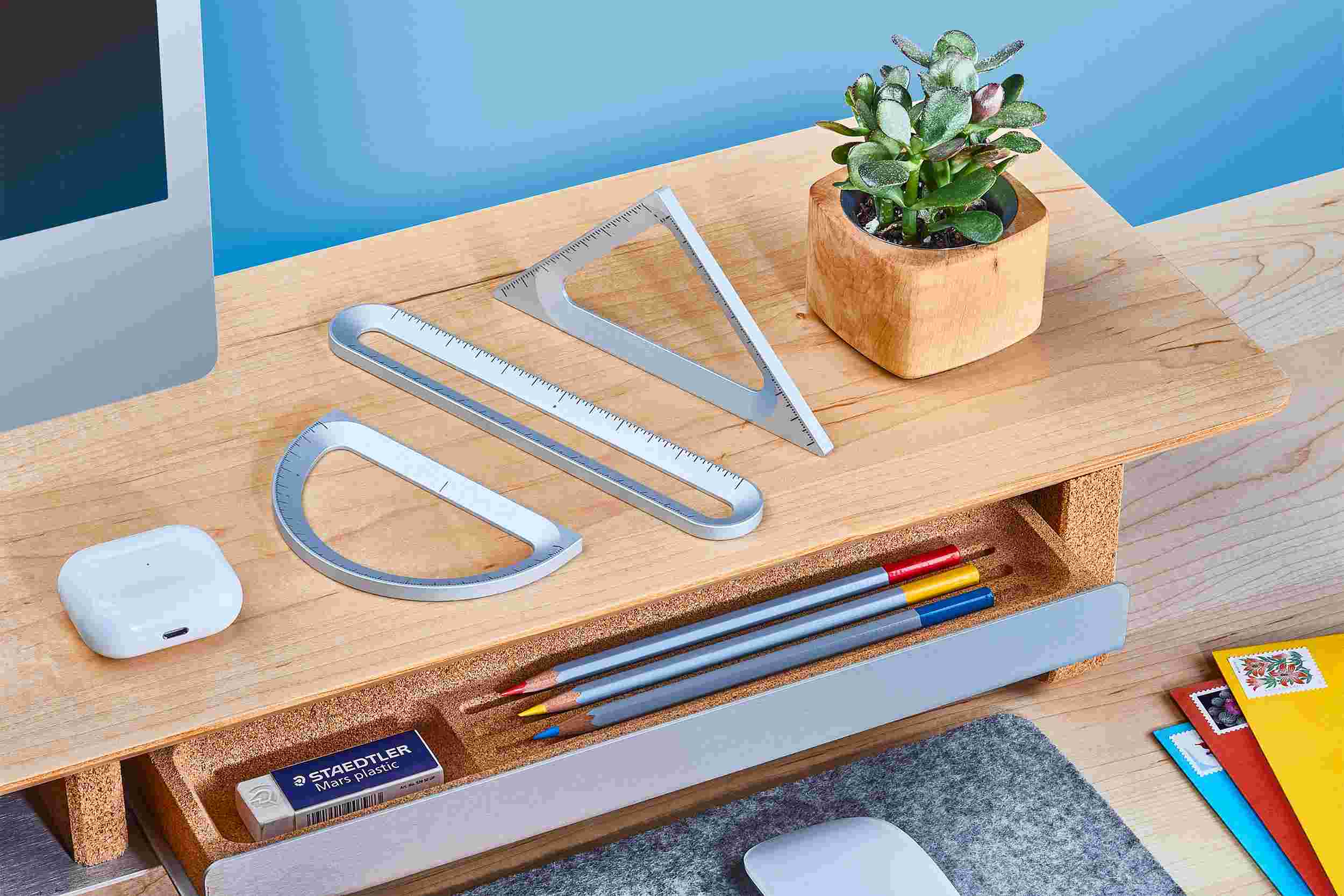 Set of three silver Grovemade measuring tools—ruler, triangle, and protractor—displayed on a maple desk shelf.