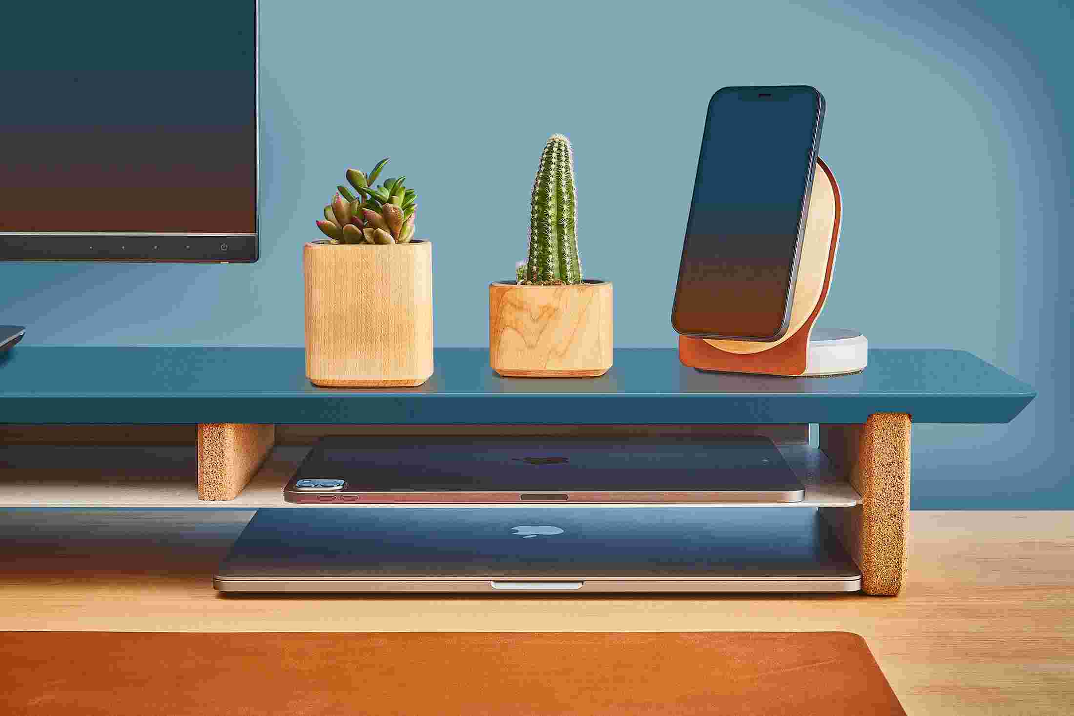 The navy desk shelf's integrated storage shelf holding a MacBook Pro.