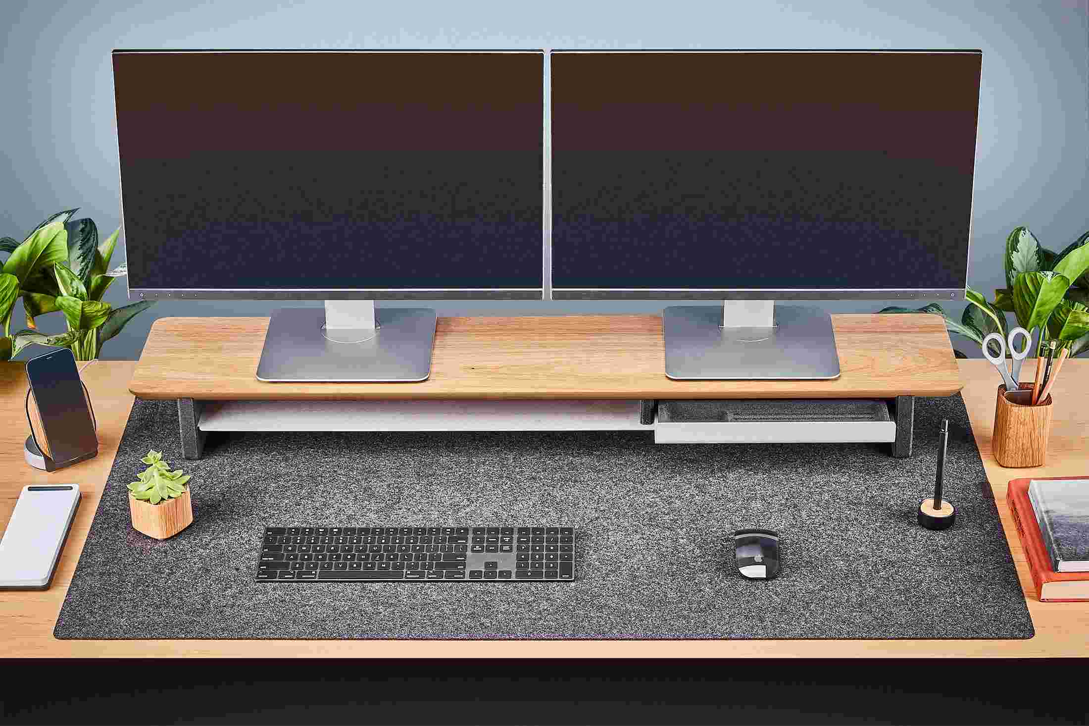 Ultra-wide oak plywood desk shelf for double monitor setup, with dark merino wool felt desk pad.