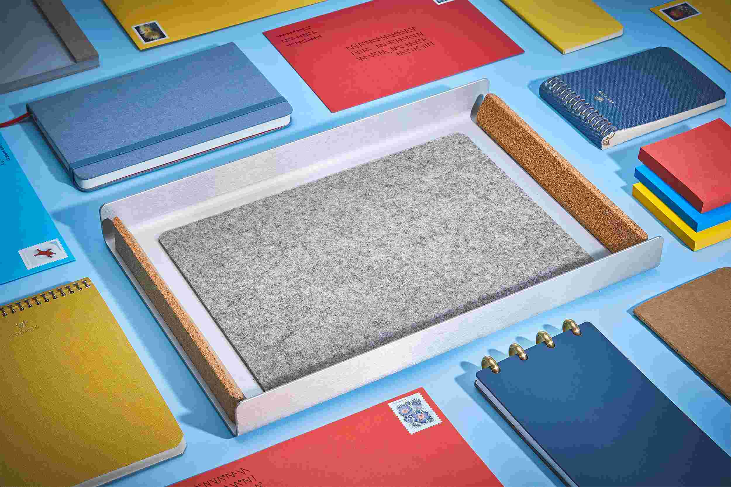 The Light Paper Tray empty and surrounded by stationery and letters on light blue.