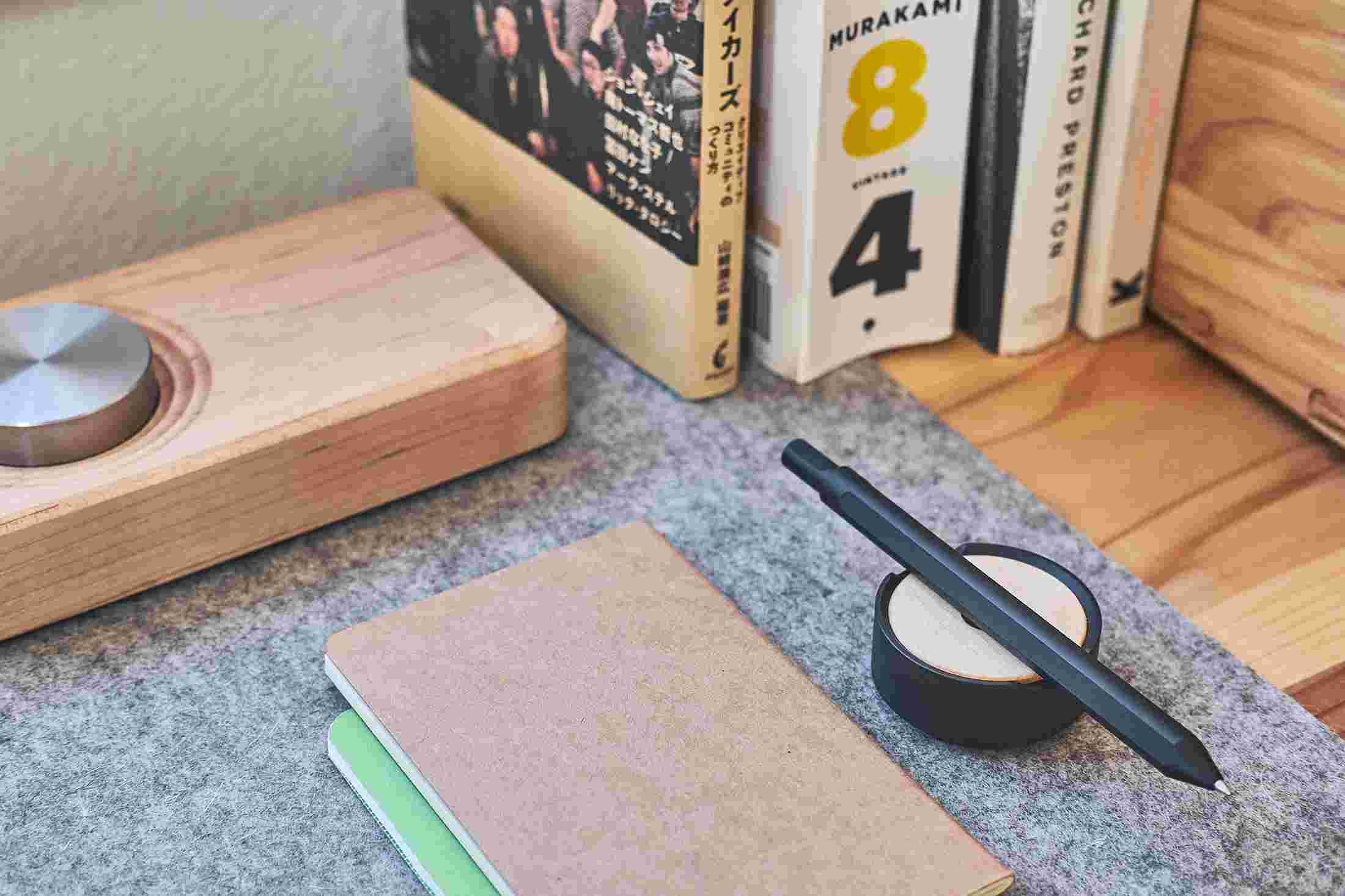 The black pen and maple wood stand on shelf.
