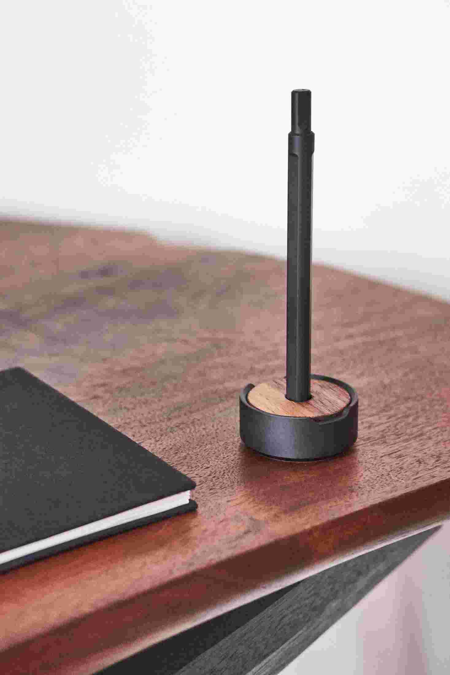The black pen and walnut wood stand with notebook.