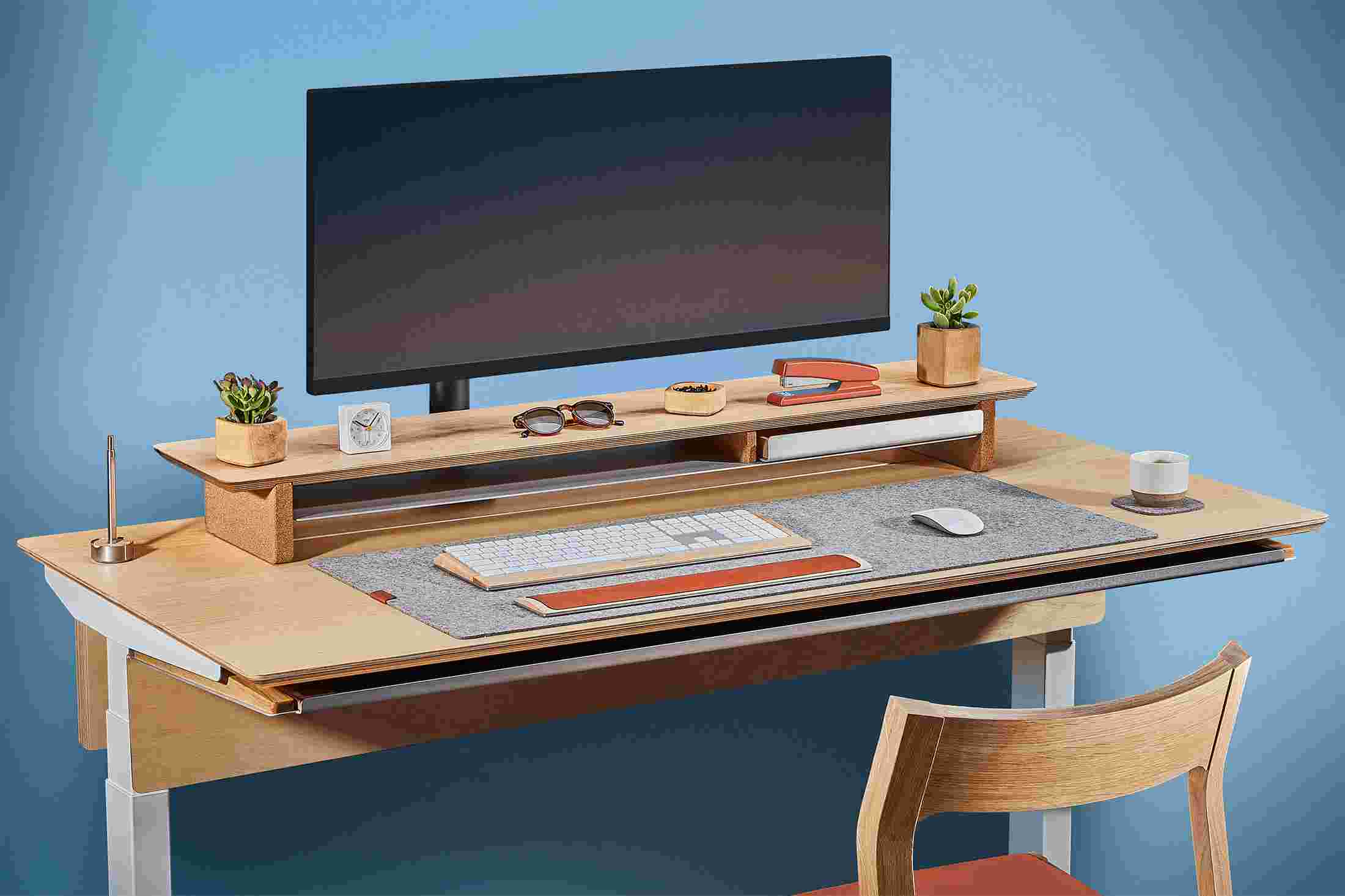 Side view of the maple plywood standing desk with monitor arm and premium felt desk pad.