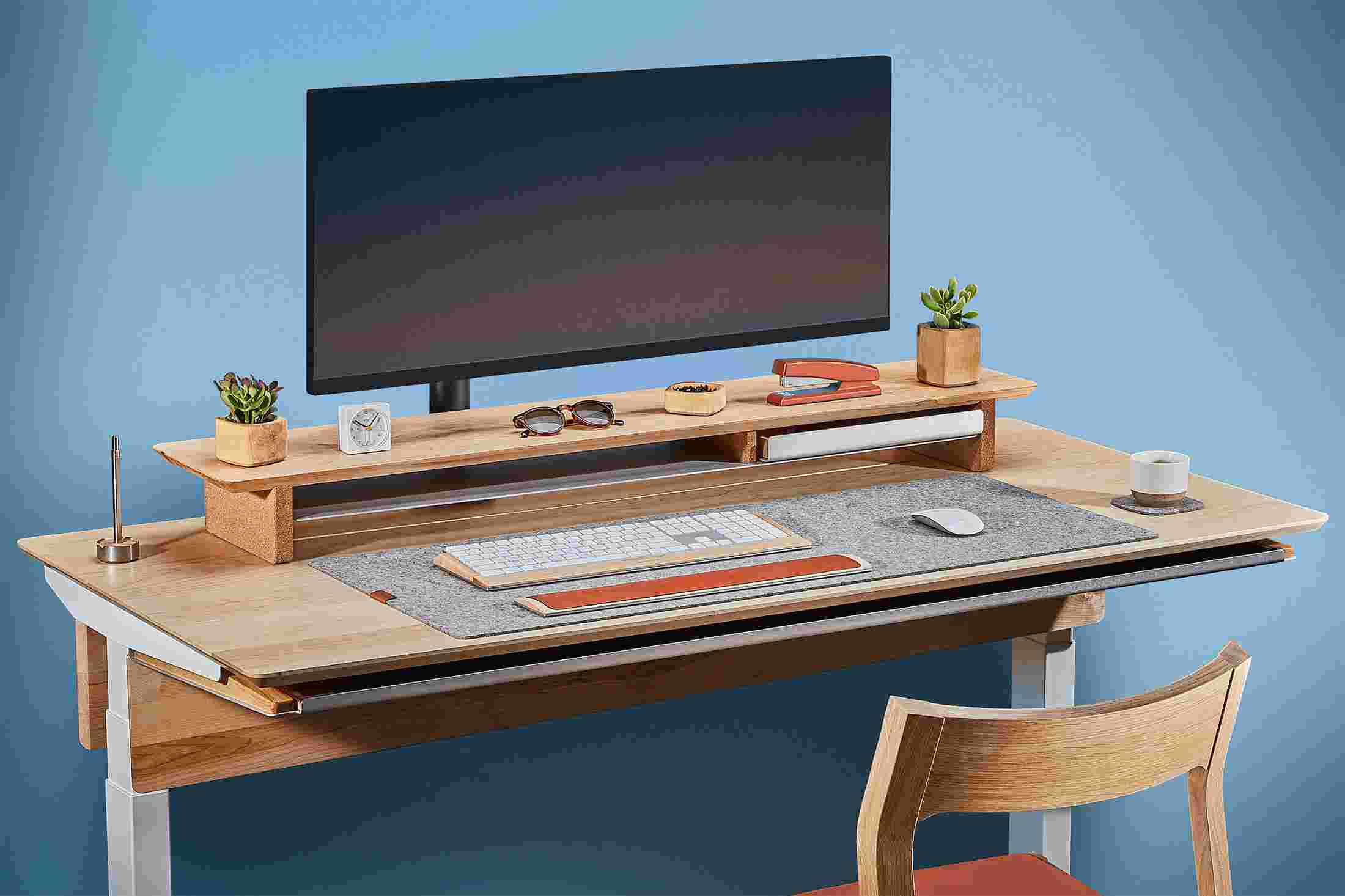 Side view of the hardwood maple standing desk with monitor arm and premium felt desk pad.