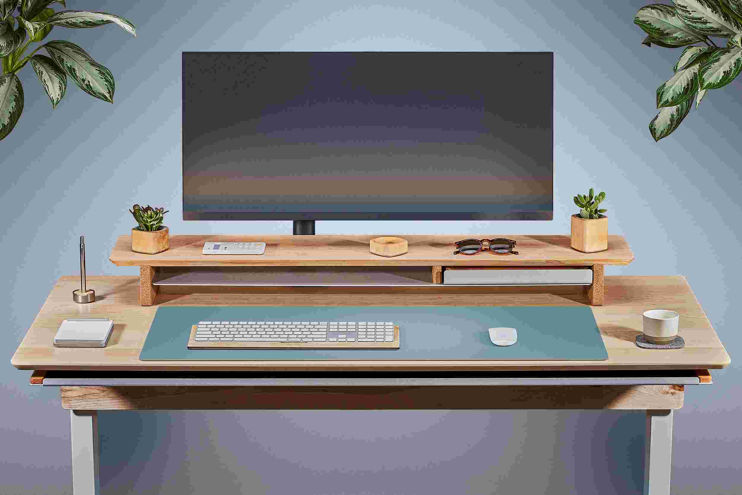 Front view of the solid maple standing desk with matching monitor stand and light blue matte desk pad.