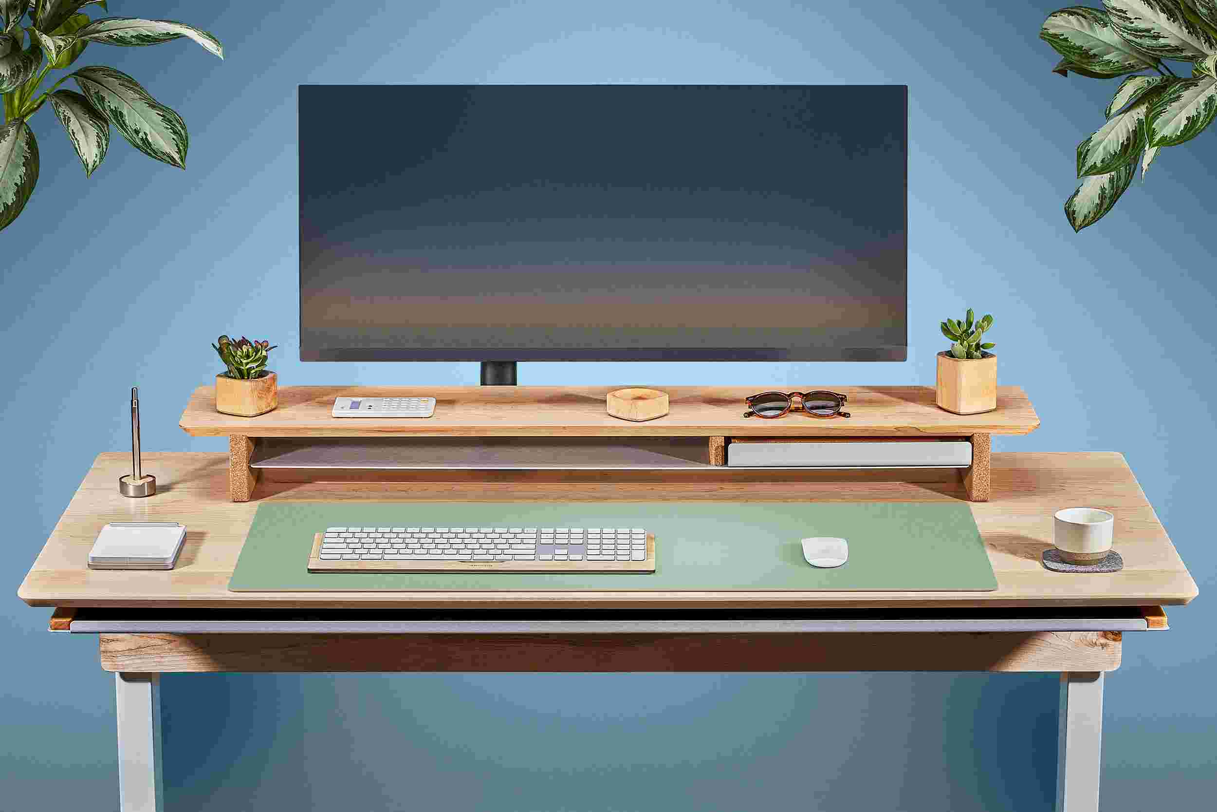 Front view of the solid maple standing desk with matching monitor stand and light green matte desk pad.