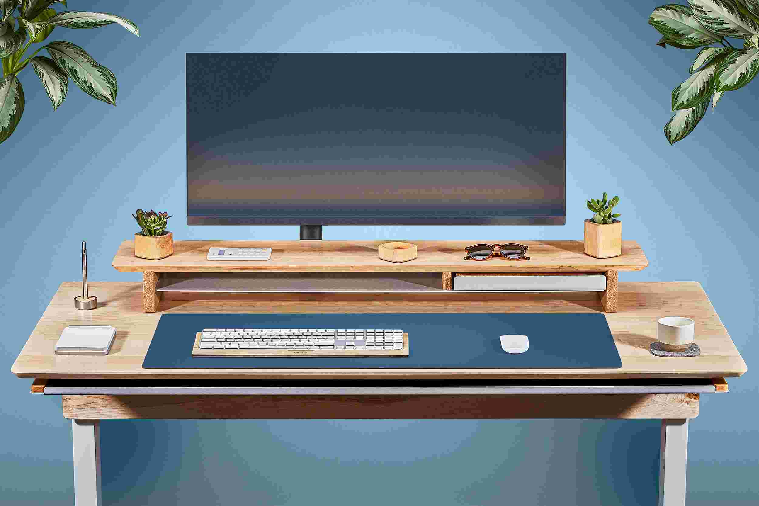 Front view of the solid maple standing desk with matching monitor stand and matte navy desk pad.