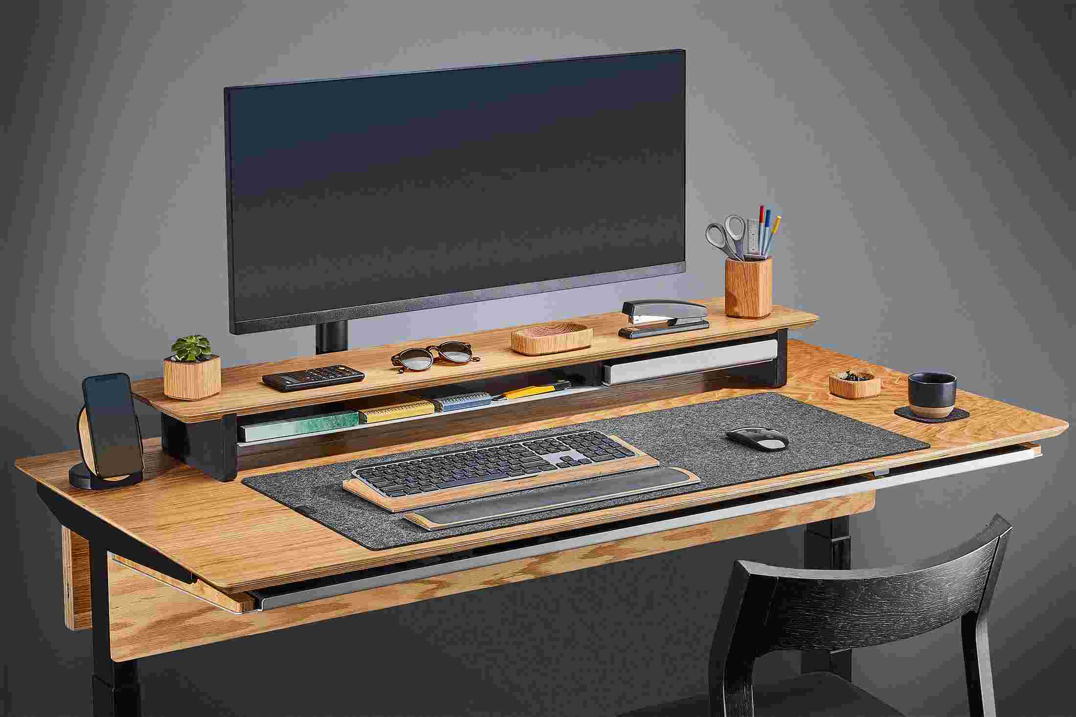 Side view of the oak plywood standing desk with monitor arm and premium felt desk pad.