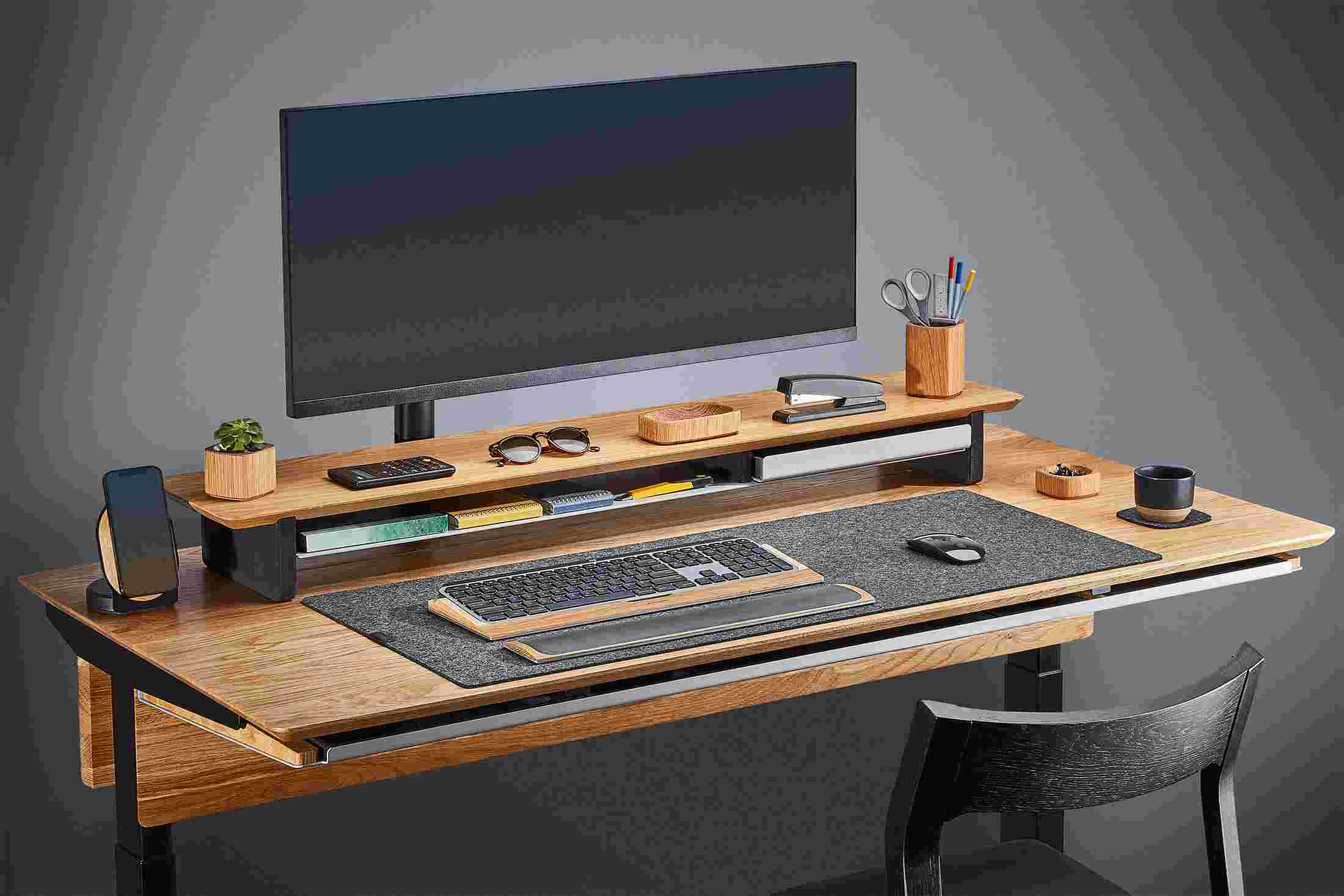 Side view of the hardwood oak standing desk with monitor arm and premium felt desk pad.