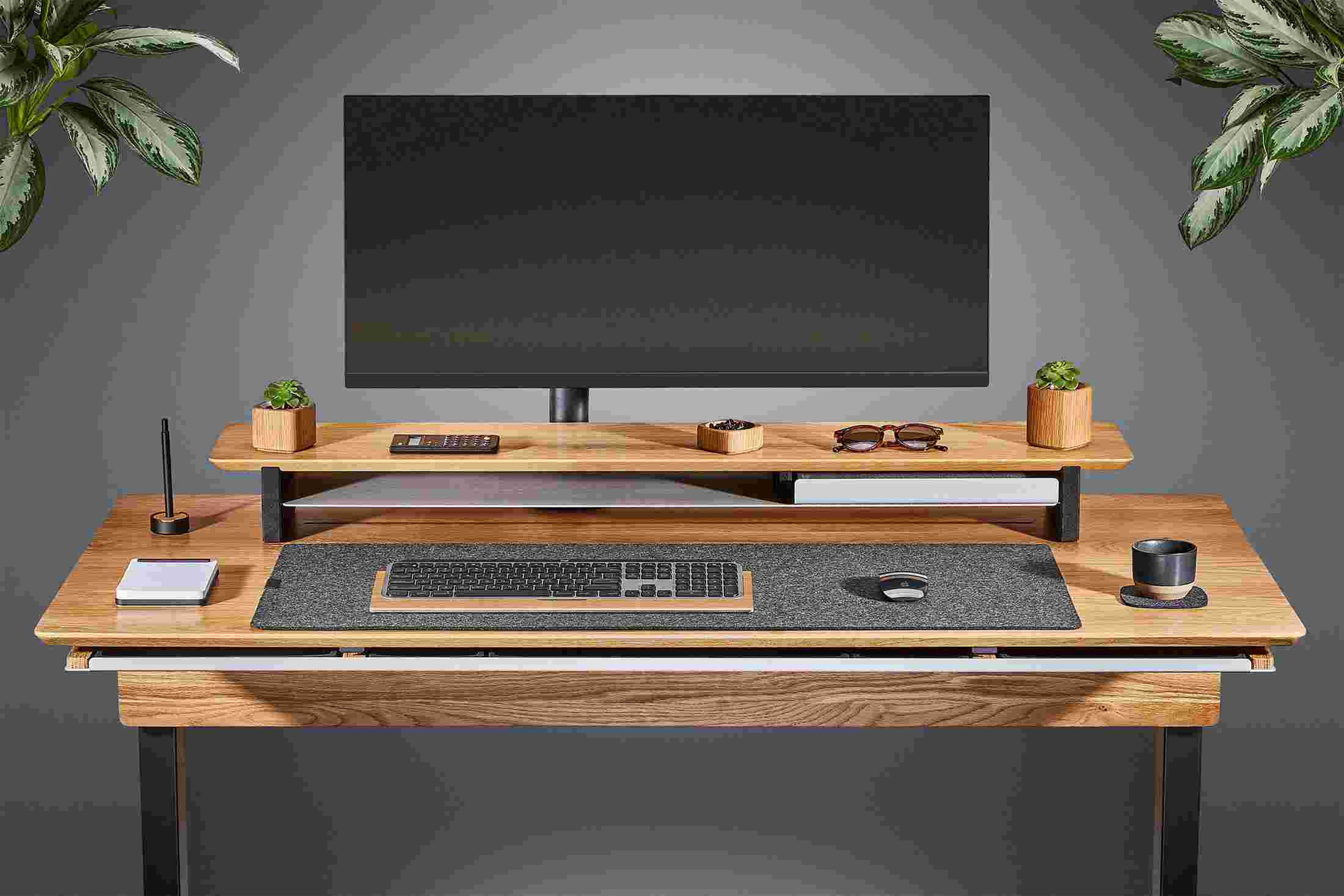 Front view of the solid oak standing desk with matching monitor stand and wool felt desk pad.