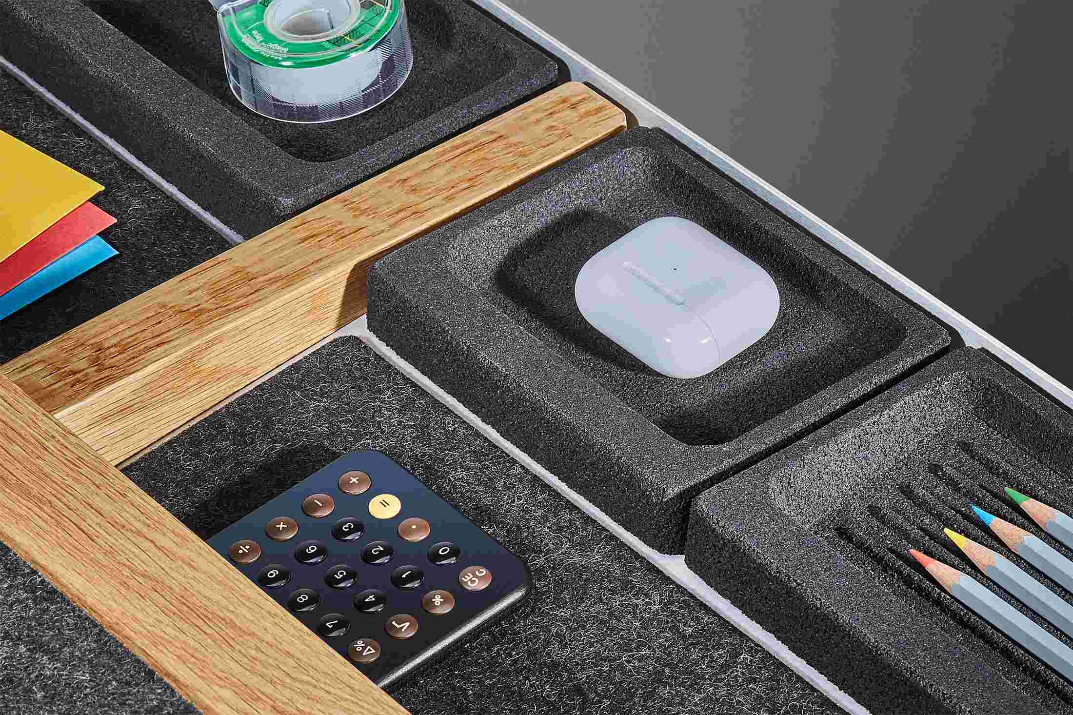 Close up detail of integrated blackened cork trays and dark wool felt lining inside of the oak desk drawer.