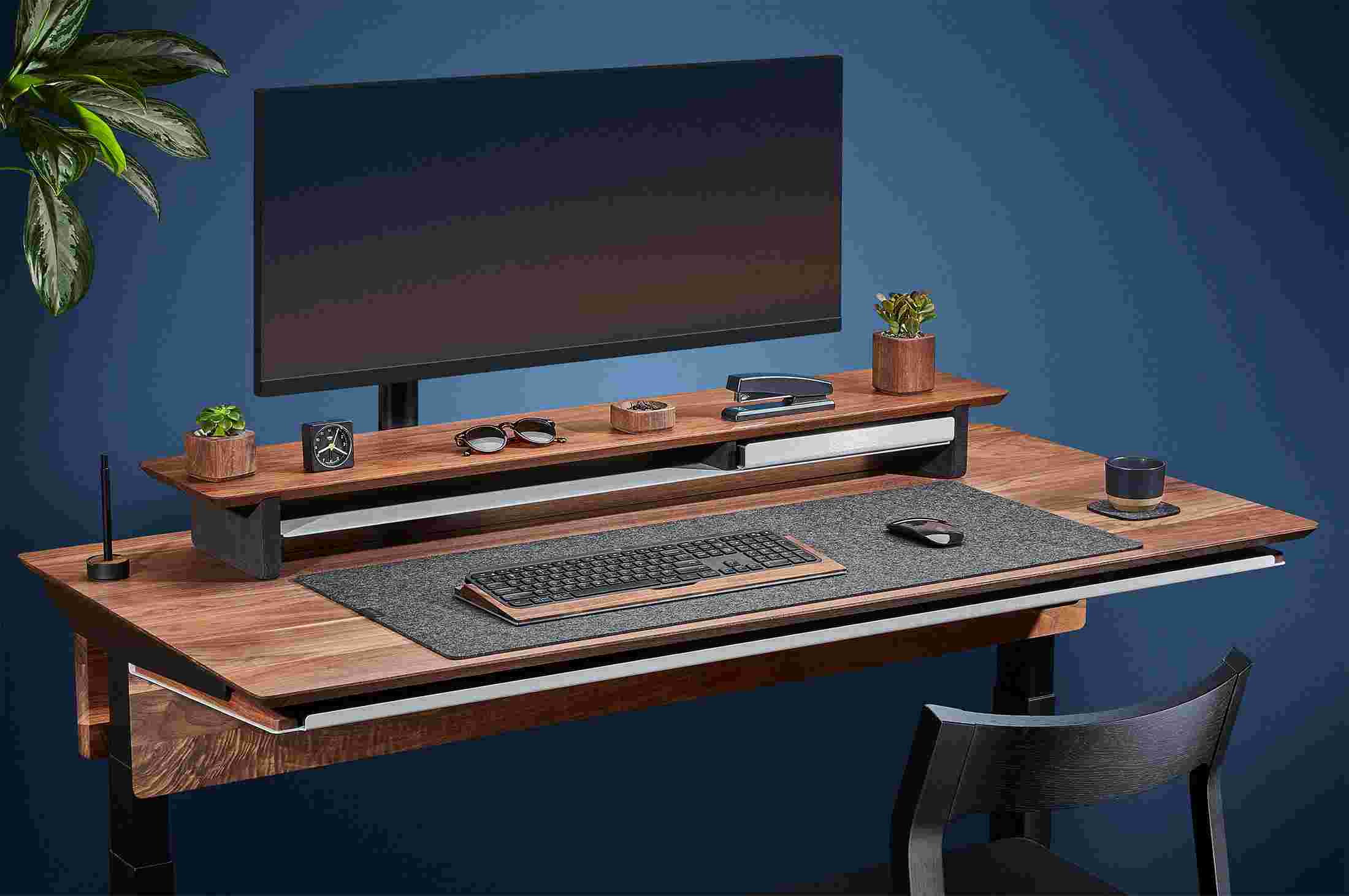 Side view of the hardwood walnut standing desk with monitor arm and premium felt desk pad.